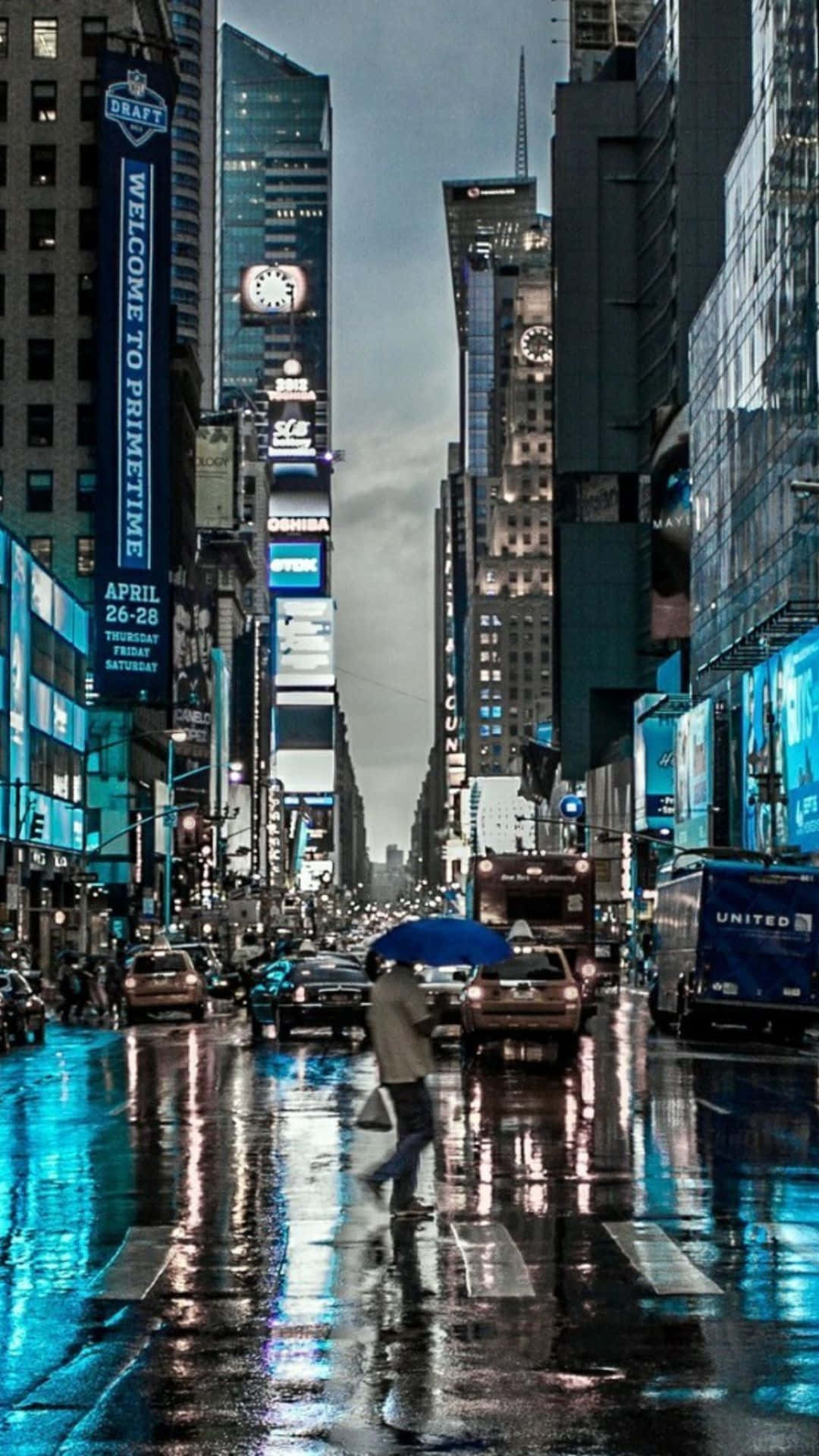 撐著藍色雨傘的人在夜晚穿過濕漉漉的城市街道，下方是發光的廣告牌。