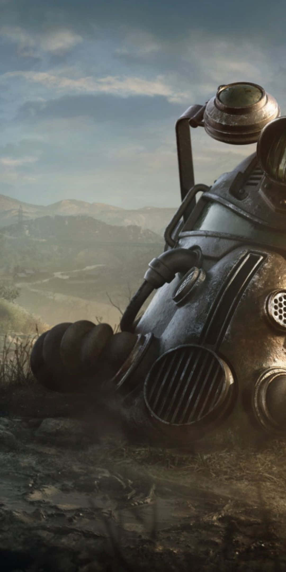 用 Google Pixel 3 踏入 Fallout 76 的輻射世界 壁紙 — 一個風化的防毒面具放置在崎嶇的地形上，背景是陰天下一片朦朧的山景。