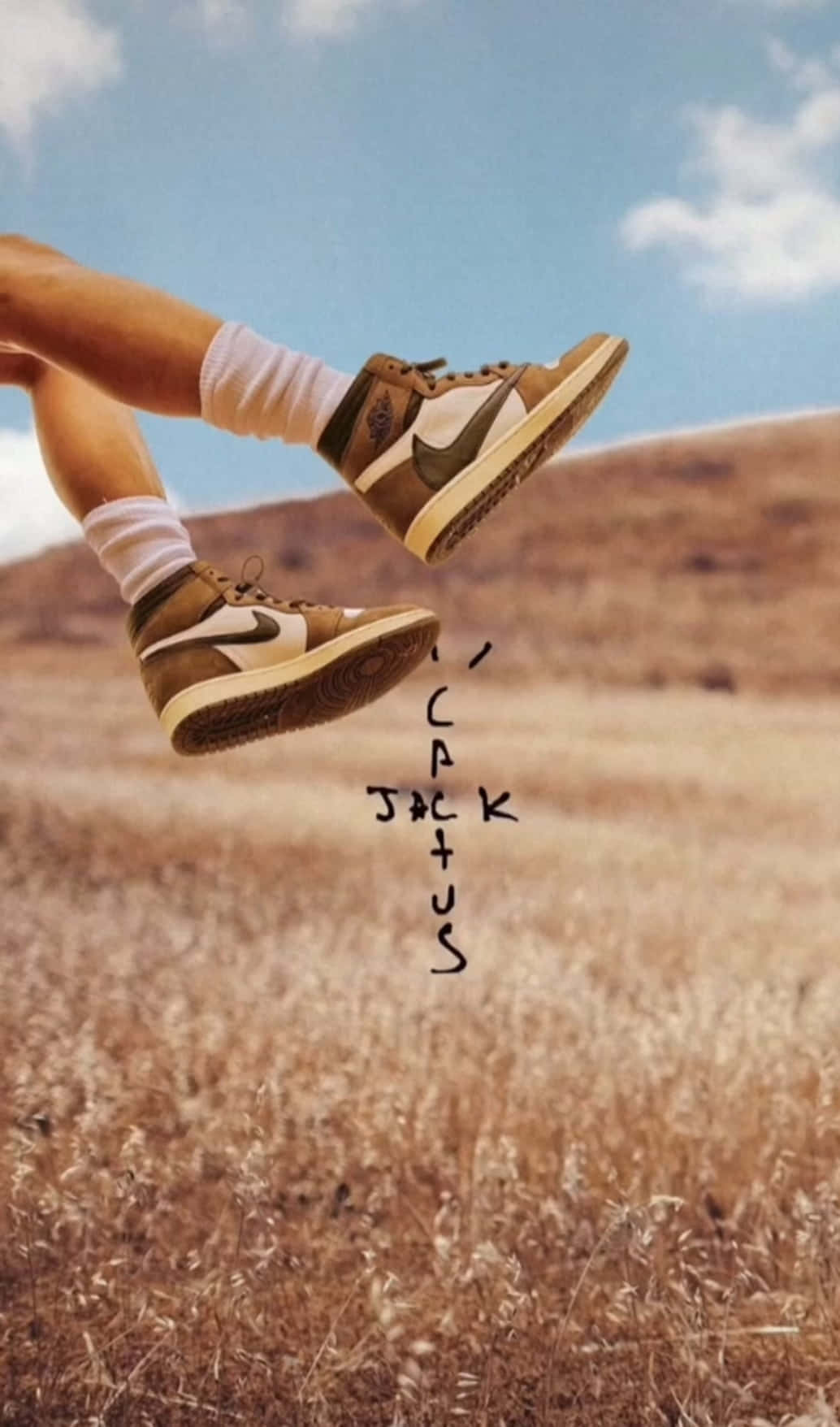 用 Hypebeast 的大膽時尚選擇提升你的街頭風格 壁紙 — 一個人的雙腿穿著棕色運動鞋，在晴朗藍天和零星白雲下，歡快地跳躍在乾燥的草地上方。