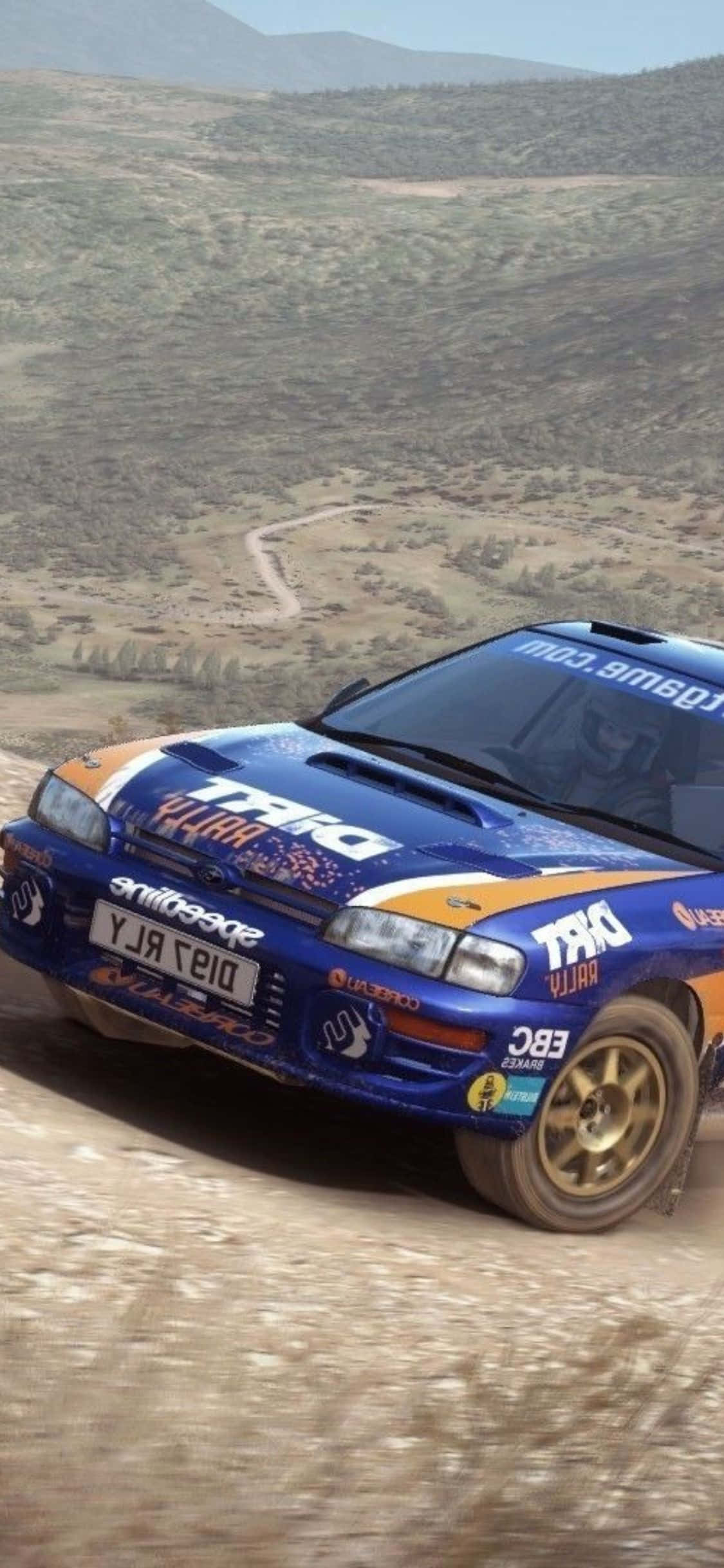 用 iPhone Xs Dirt Rally 攻克賽道 壁紙 — 一輛藍色和橙色的拉力賽車在塵土飛揚的山路上飛馳，背景是崎嶇的山丘。