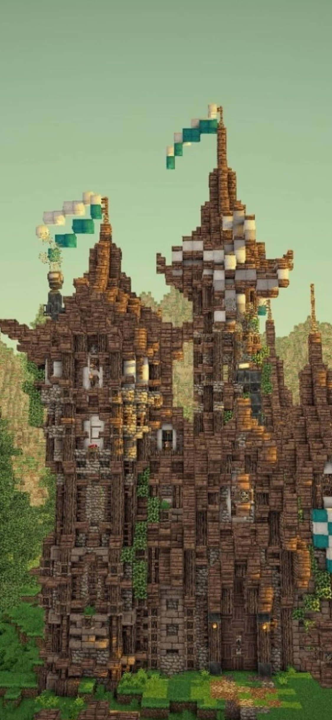 用 iPhone Xs 探索 Minecraft 的新世界 壁紙 — 一座由棕色方塊砌成、高聳的像素化城堡，帶有綠色藤蔓和青綠色旗幟，背景是柔和的綠色天空。