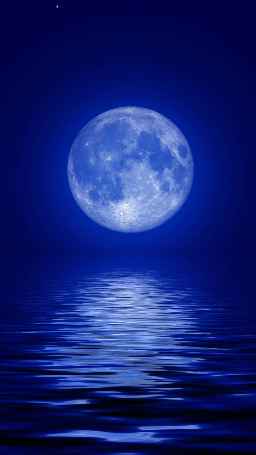 用 Moon iPhone 感受夜空的自然之美 壁紙 — 一輪明亮的滿月在深邃的夜空下，照耀著平靜的藍色水面，映照出其寧靜的光芒。