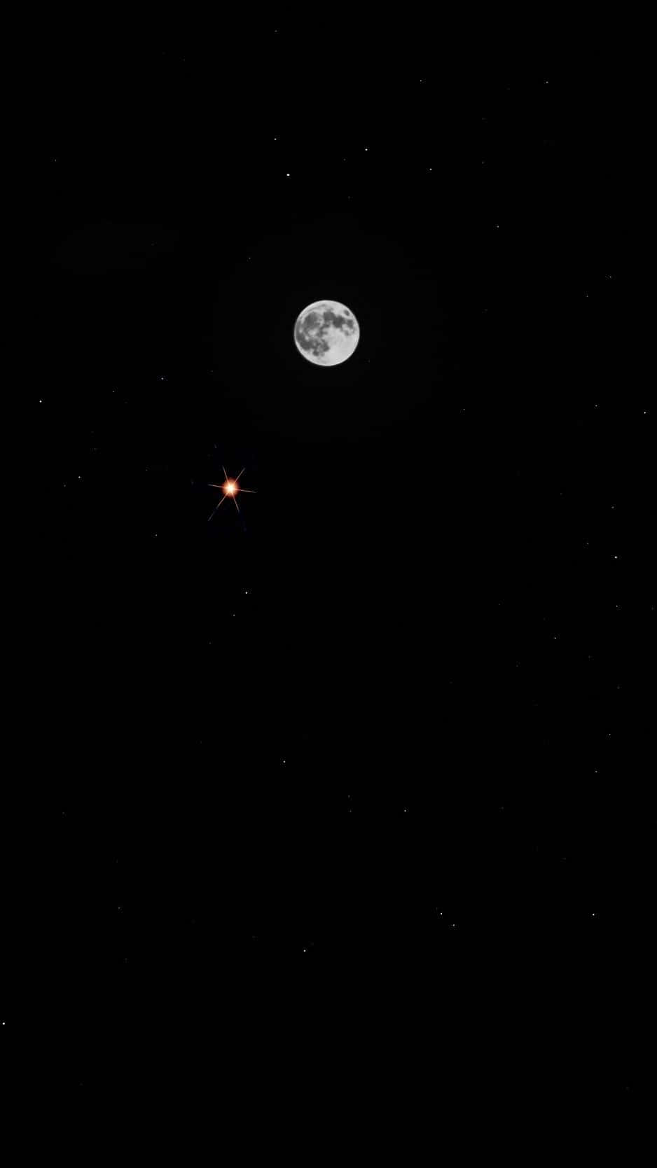 用 Moon iPhone 沉浸繁星璀璨的夜晚 壁紙 — 一輪明亮的滿月懸掛在繁星點點的夜空中，附近有一顆明亮的橙色星星閃耀。