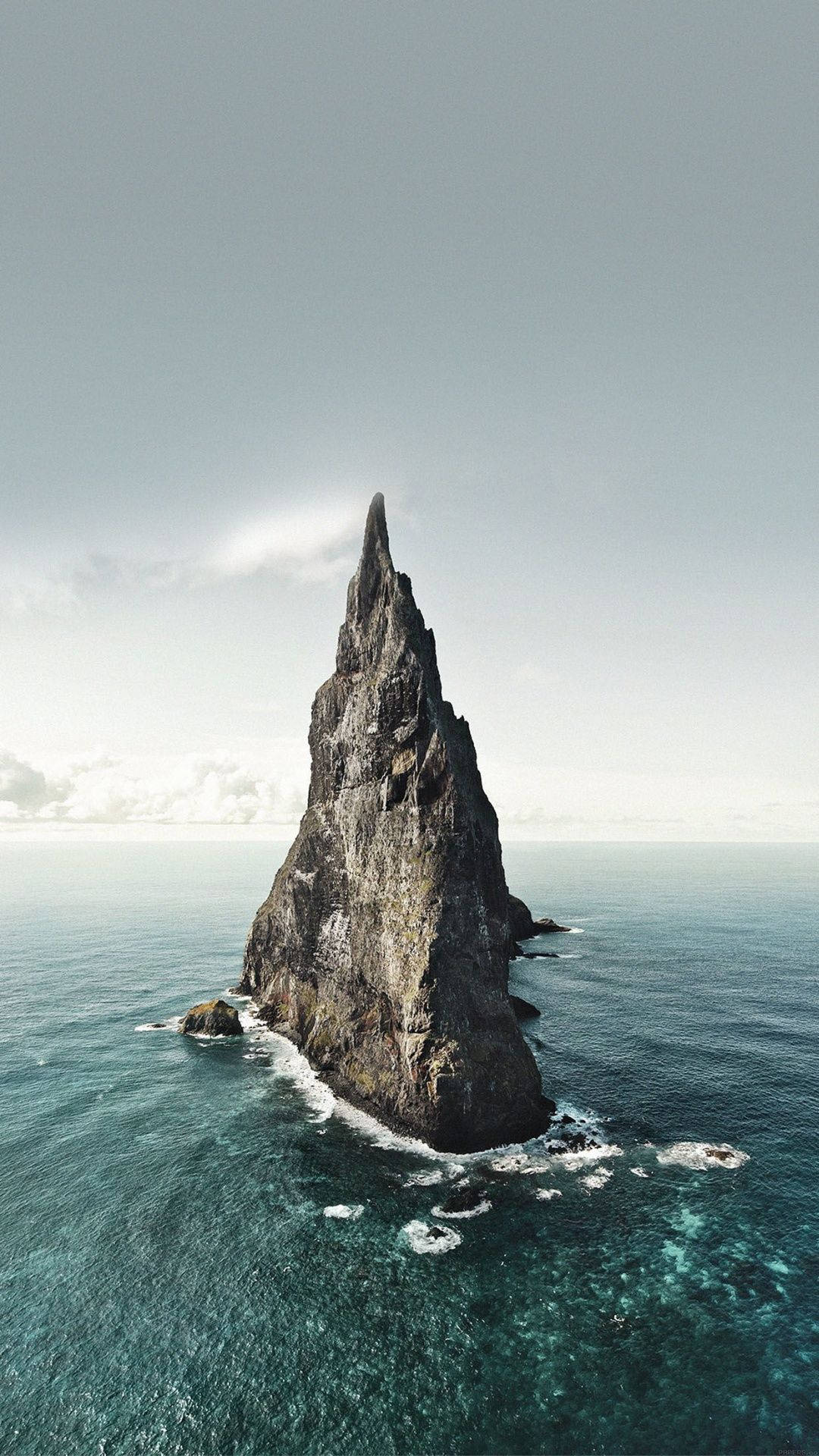 在陰天之下，一座孤獨地矗立在海中的高聳岩石島嶼。