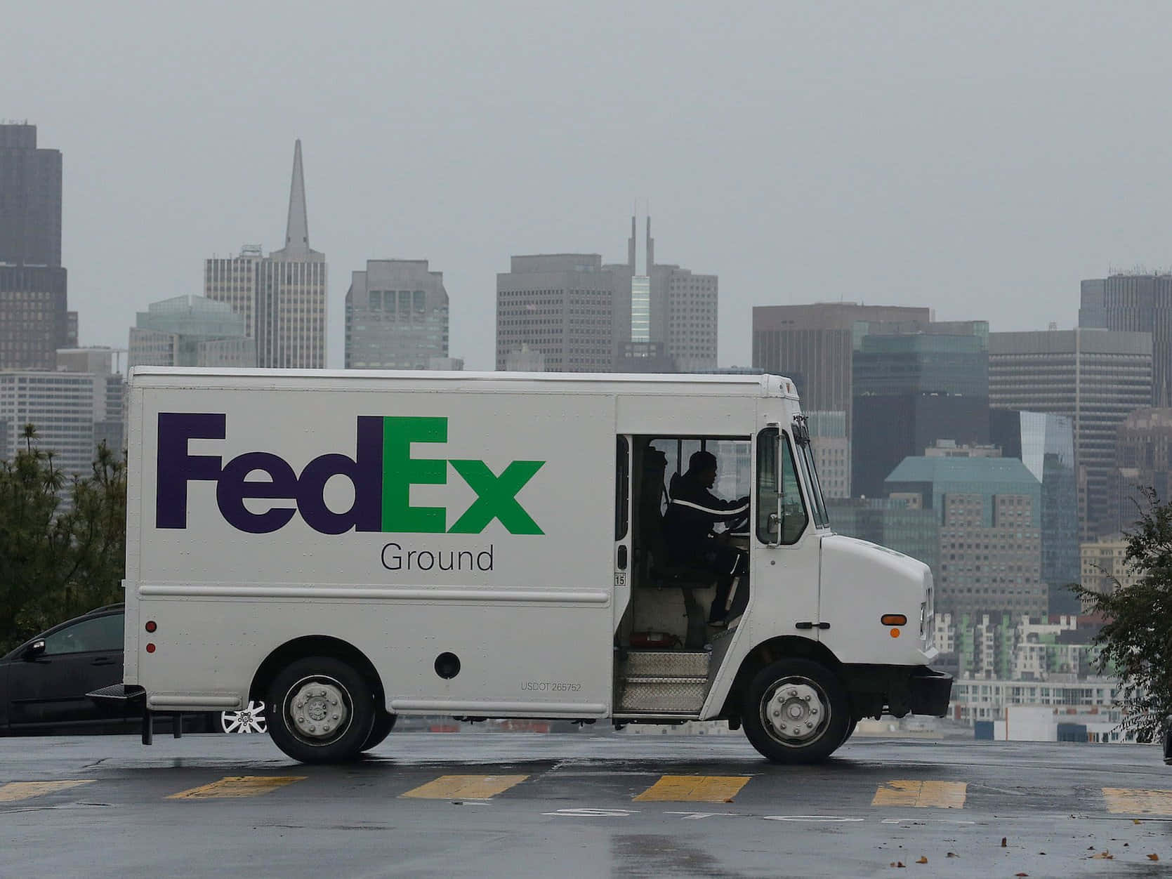 FedEx貨車停泊在雨天城市，背景有天際線