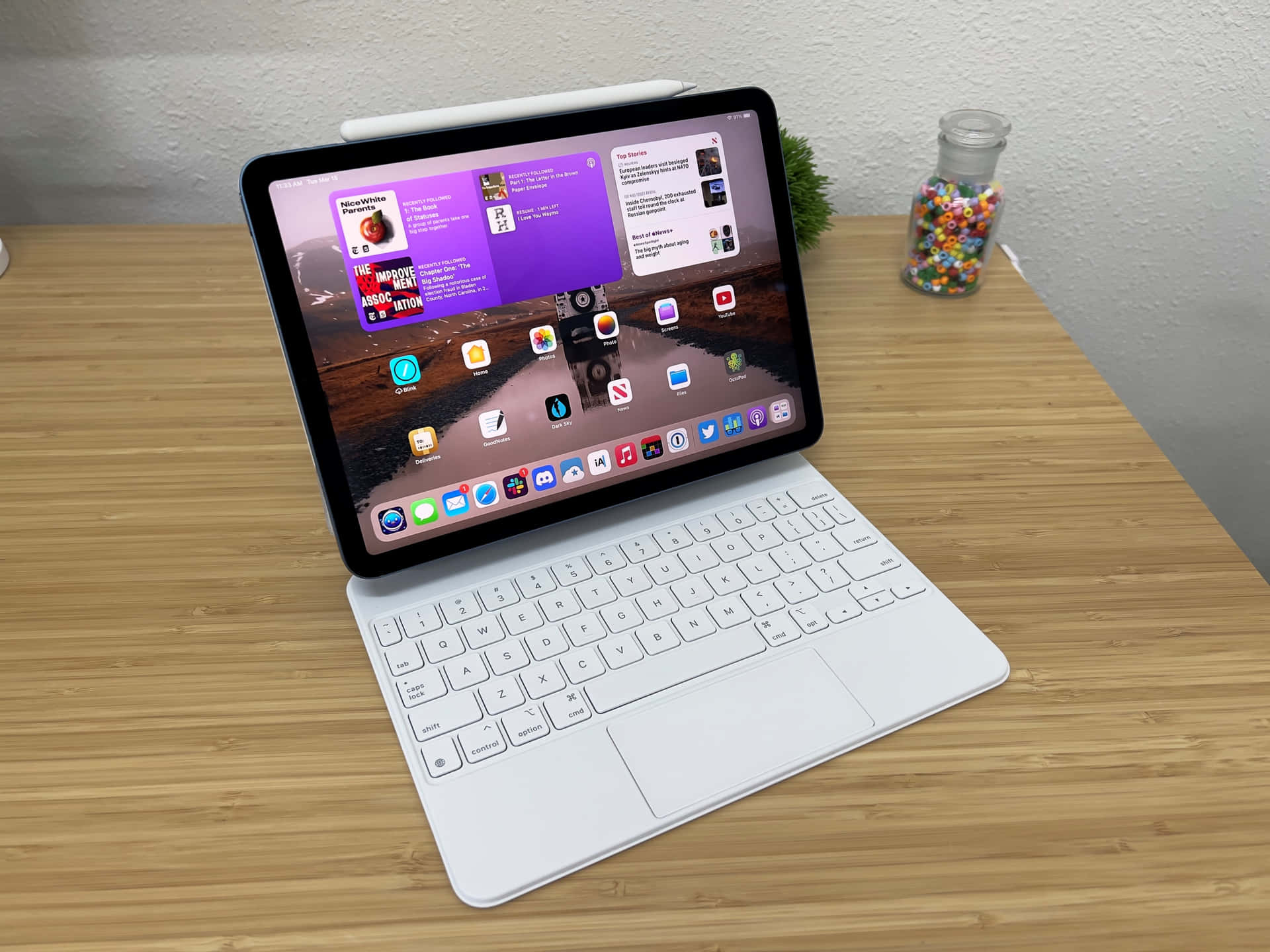 白色iPad連鍵盤保護套放在木桌上，顯示應用程式圖標和紫色壁紙。