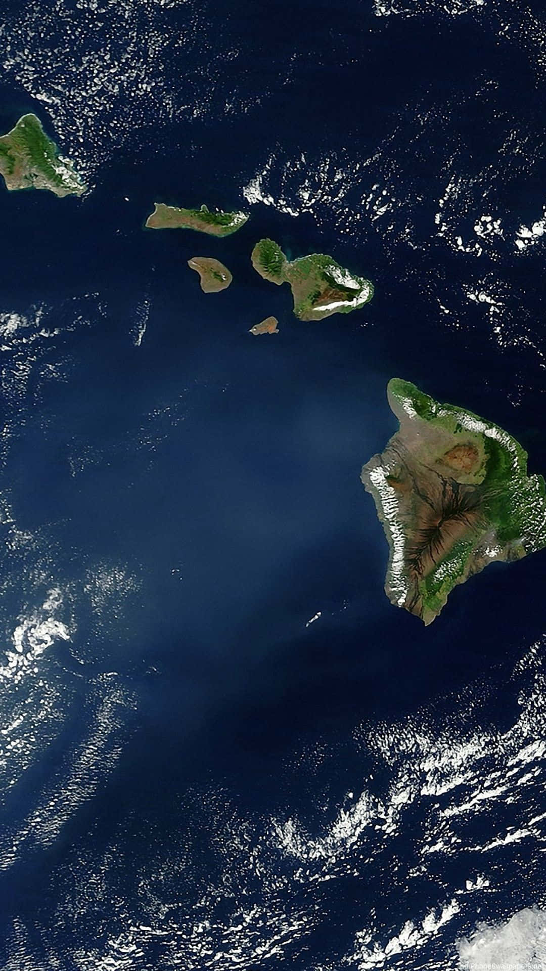 海洋中火山島的衛星圖像，有綠色森林和白色雲朵。