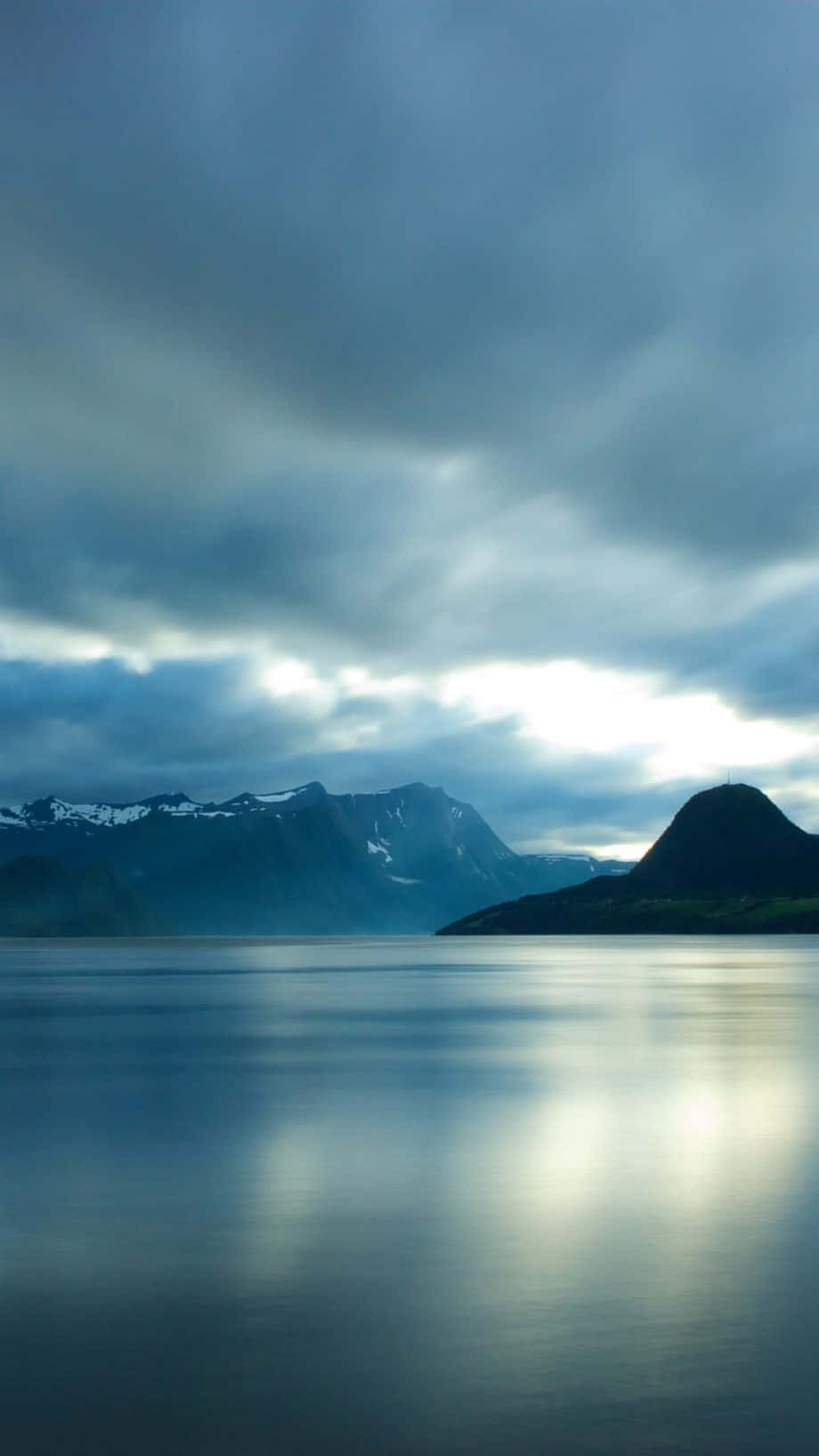 寧靜的山湖映照著戲劇性的雲彩和白雪覆蓋的山峰。