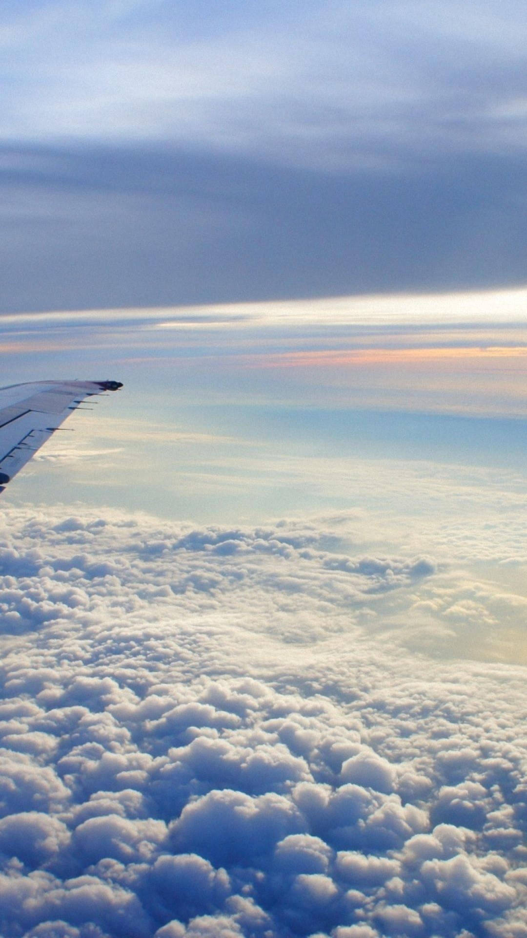 日落時分飛機機翼在蓬鬆雲層之上