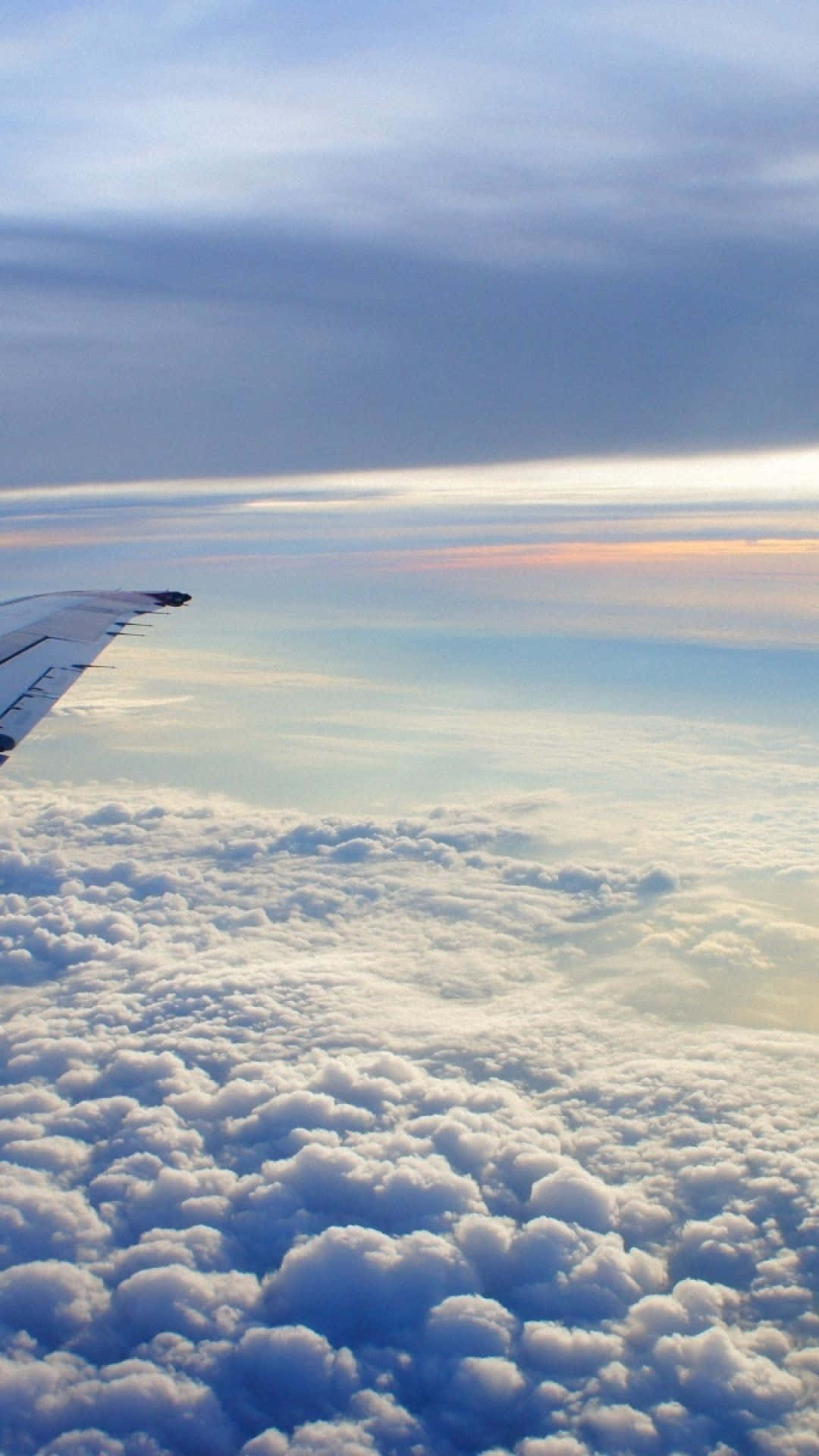 日出時蓬鬆雲層上的飛機機翼