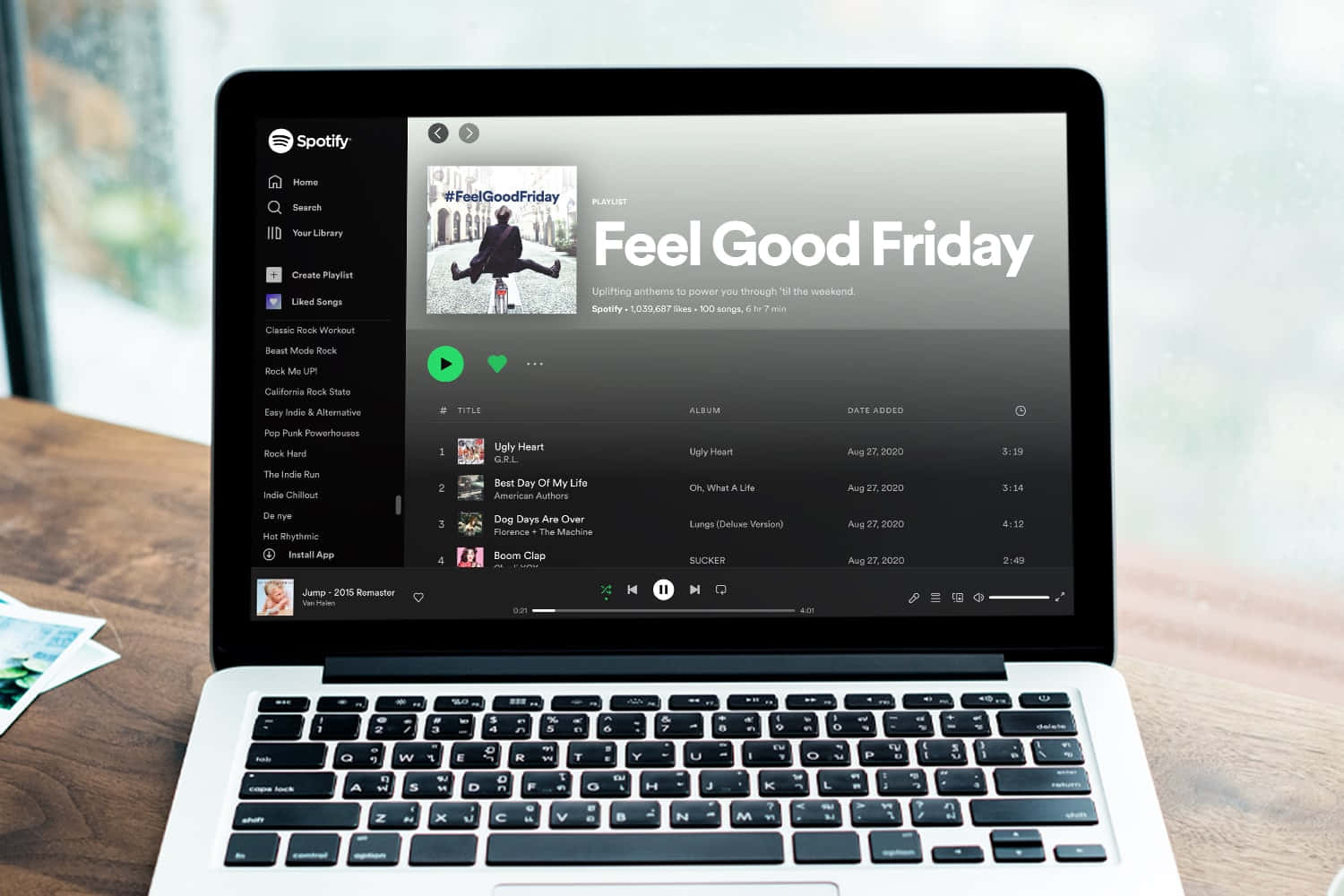 手提電腦在窗邊的木桌上顯示 Spotify 的「Feel Good Friday」播放清單。
