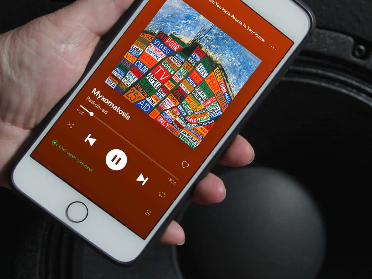 手裡拿著手機，在車內播放帶有文字藝術封面的 Radiohead 音樂。