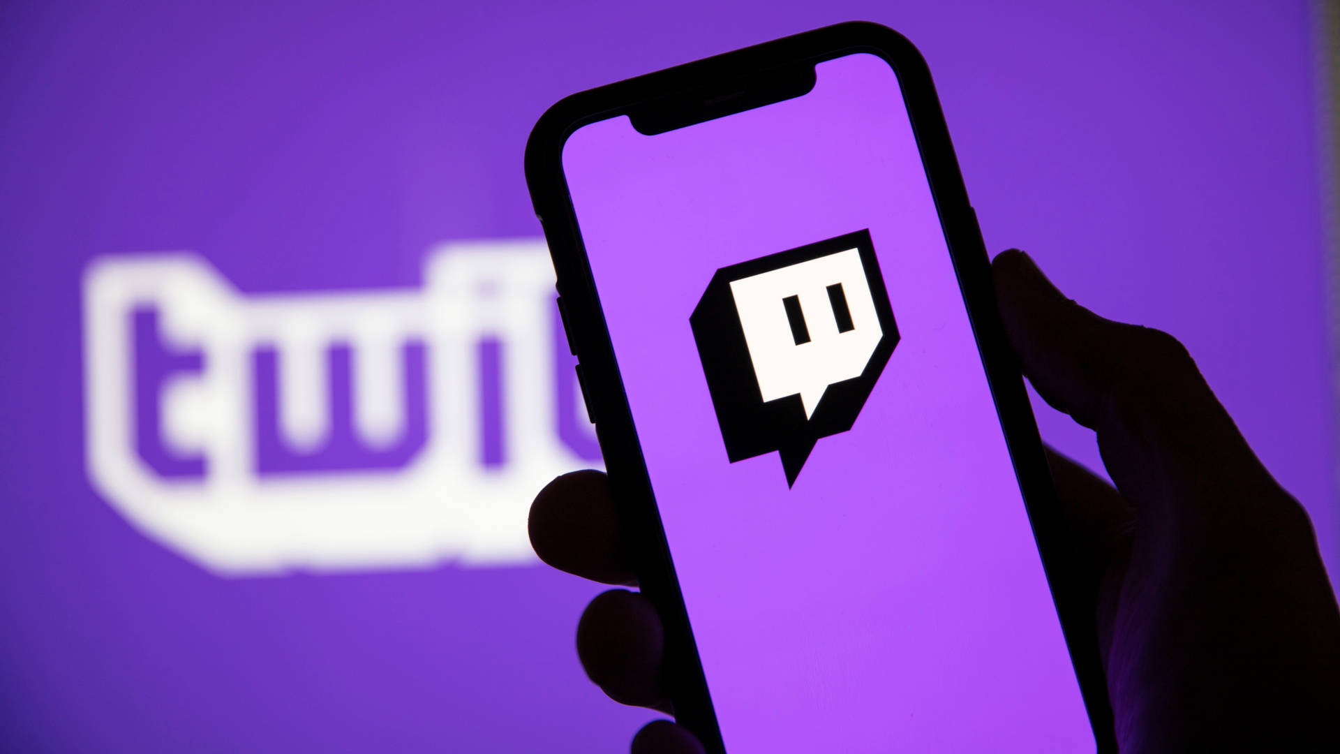 手拿著電話，顯示 Twitch 應用程式標誌，紫色背景。