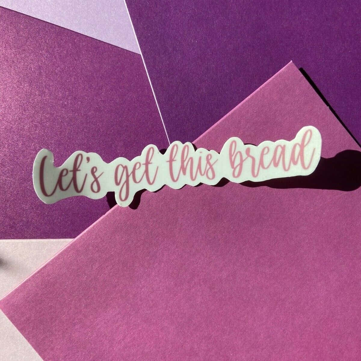 一張紫色紙上的勵志貼紙，上面寫著「Let's get this bread」。