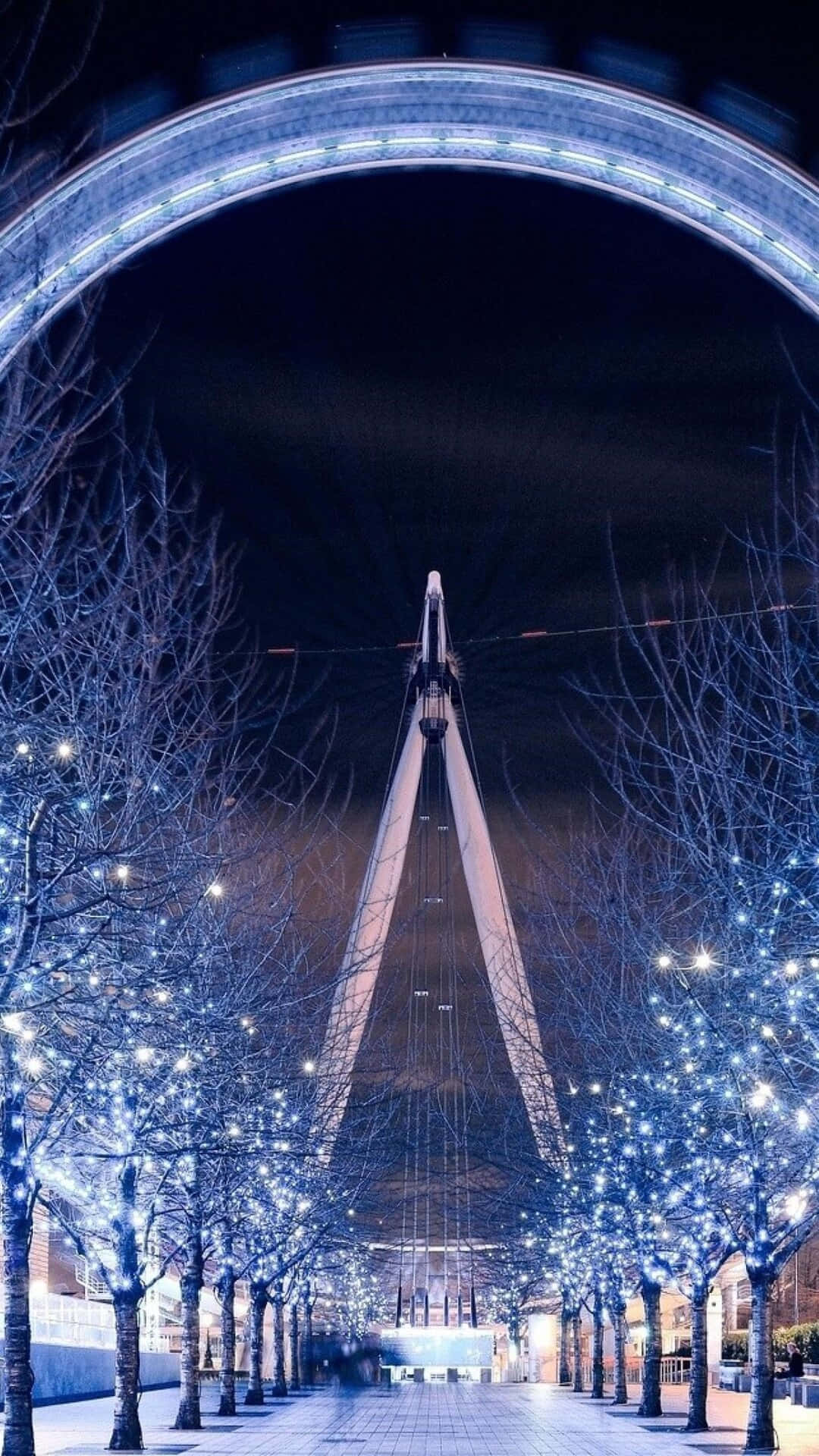 夜晚發光的摩天輪，周圍是覆蓋著雪的樹木和藍色燈光。