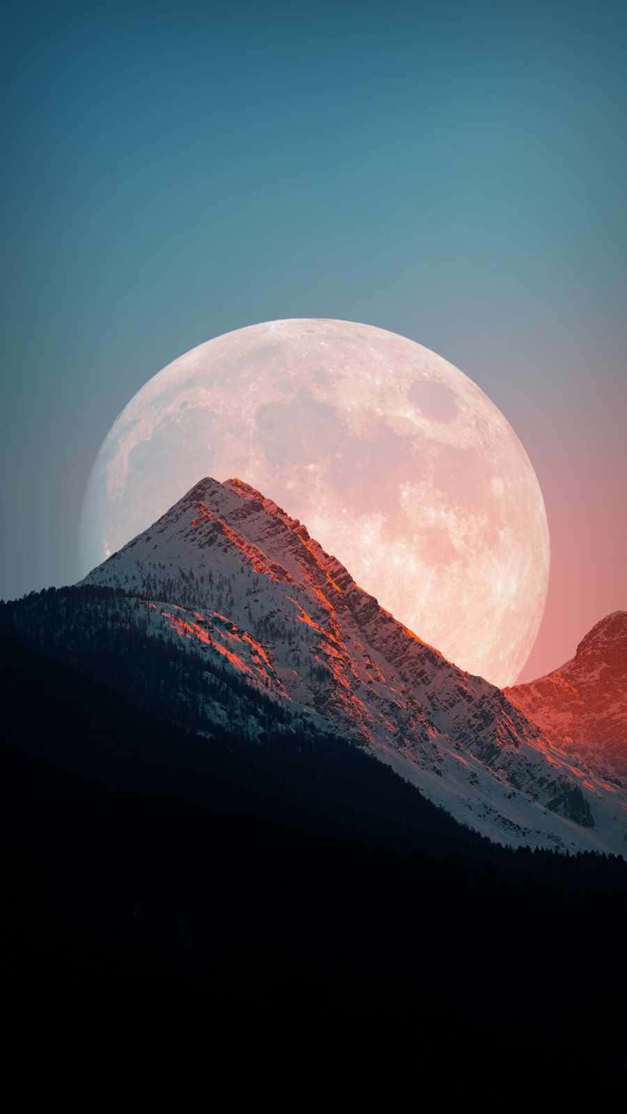 用月相 iPhone 照亮你的世界 壁紙 — 暮色中，一座積雪的山峰在巨大的粉紅色和藍色發光月亮襯托下呈現剪影。