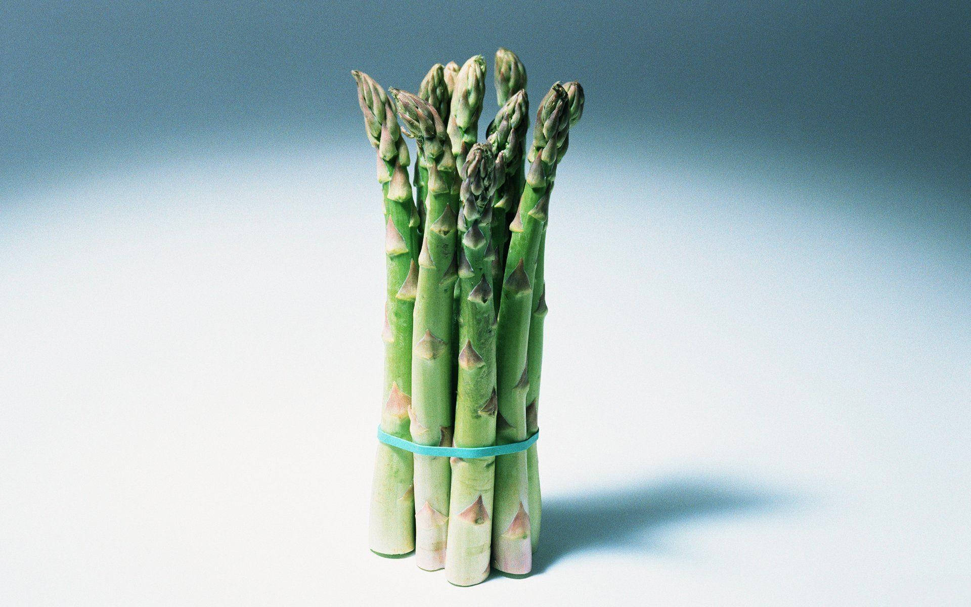 新鮮的綠蘆筍用藍色帶子綁著，放在淺色背景上。