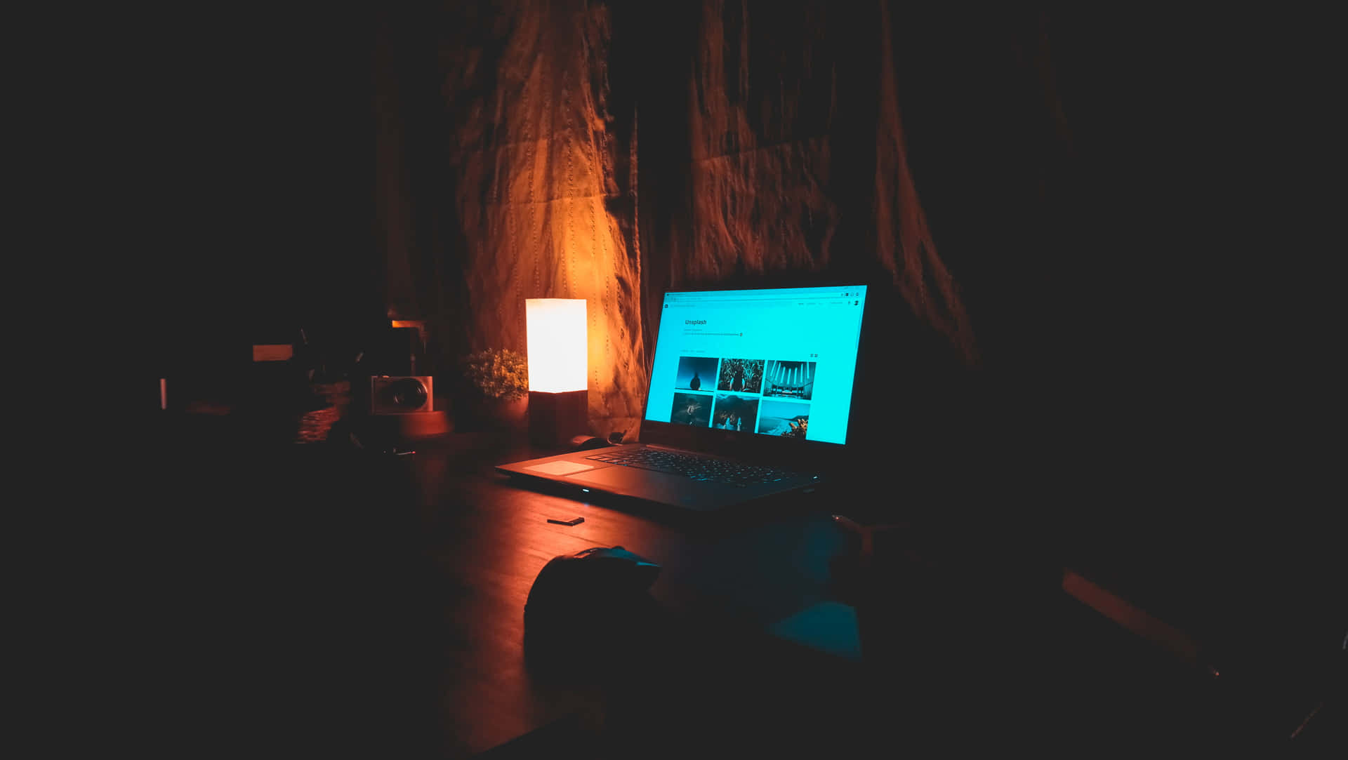 夜晚在黑暗的房間裡發光的筆記型電腦和燈。