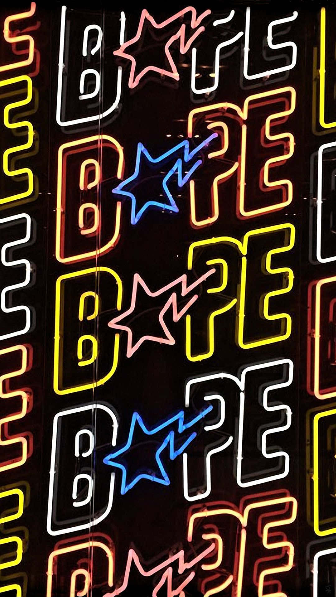 用這款 Bape iPhone 6 壁紙展現你的個性！ 壁紙 — 鮮豔的霓虹燈在深色牆壁上以鮮豔色彩發光，牆上顯示重複的「BAPE」標誌和星星圖案。