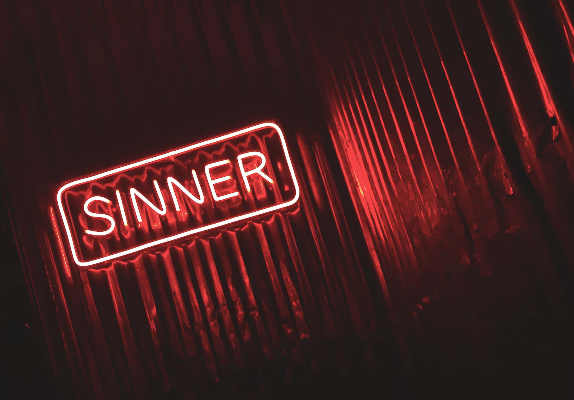 夜間波紋金屬牆上寫著「SINNER」的紅色霓虹燈牌。
