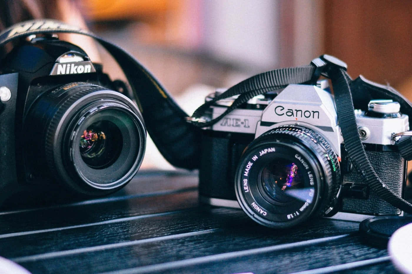兩部經典菲林相機Nikon和Canon放在木桌上。