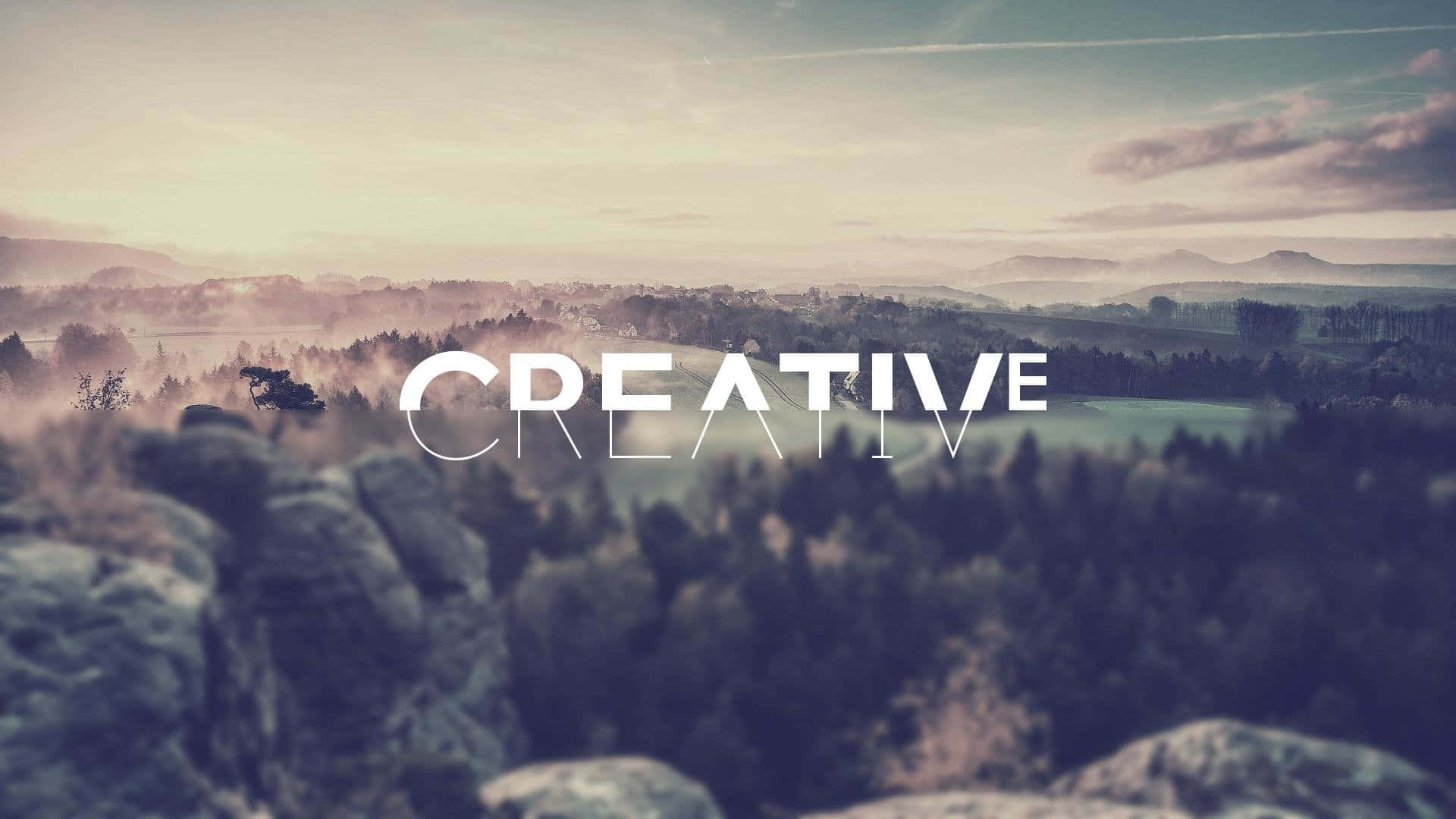 黎明時分霧氣瀰漫的山谷，上面覆蓋著單詞CREATIVE。