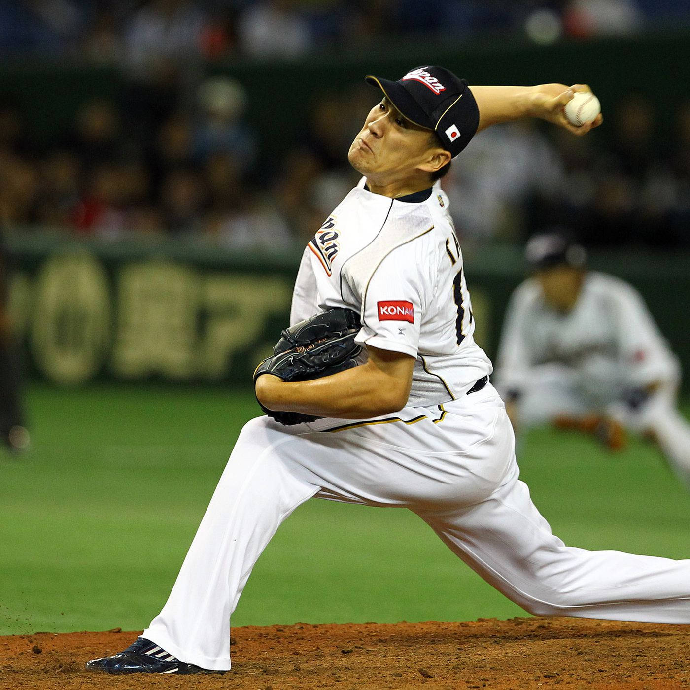田中將大激烈投球 壁紙 — 一名身穿白色球衣的棒球投手在球場燈光下專注地投球。