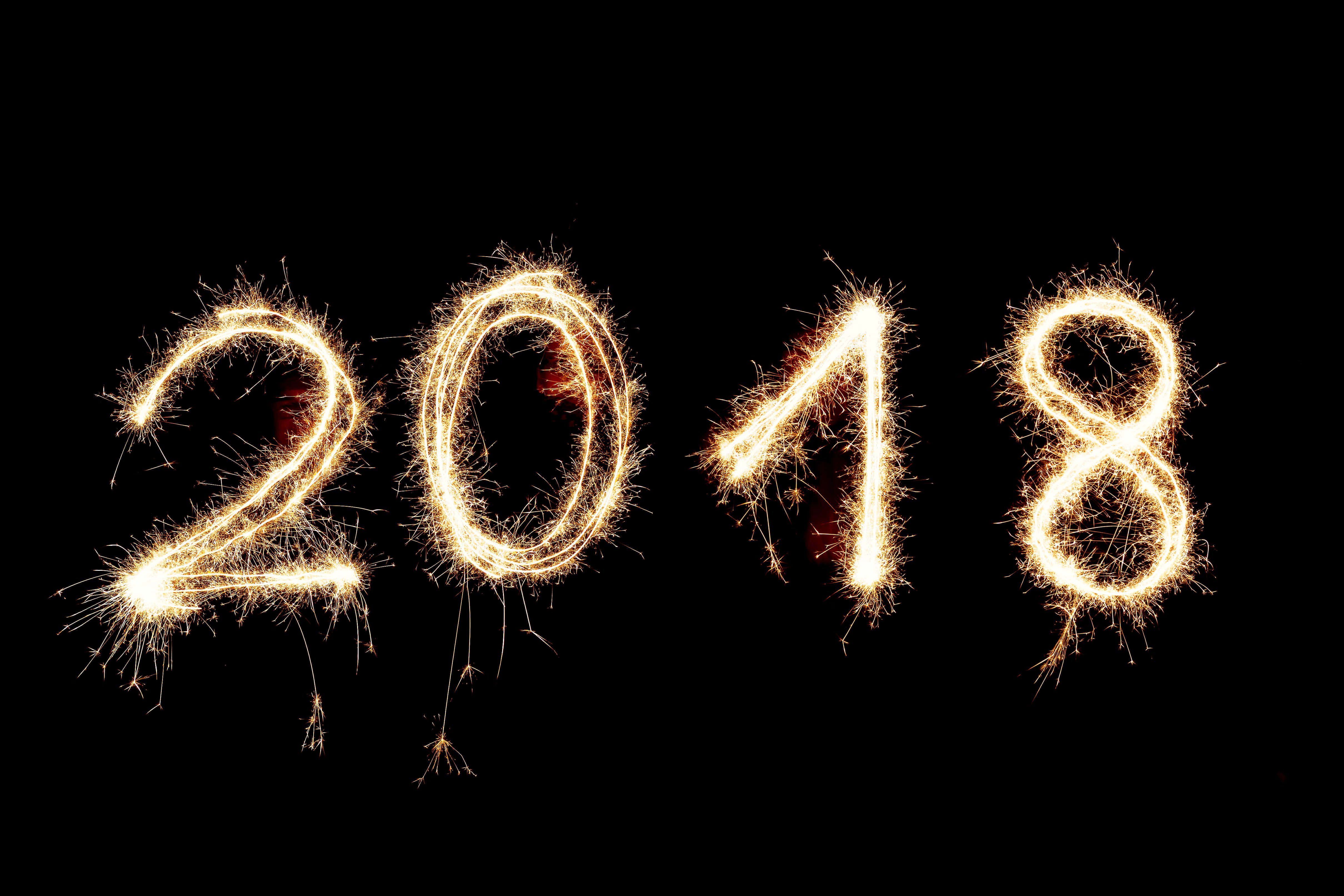 2018 桌布 壁紙 — 由發光的金色煙火在純黑背景上形成的2018年。