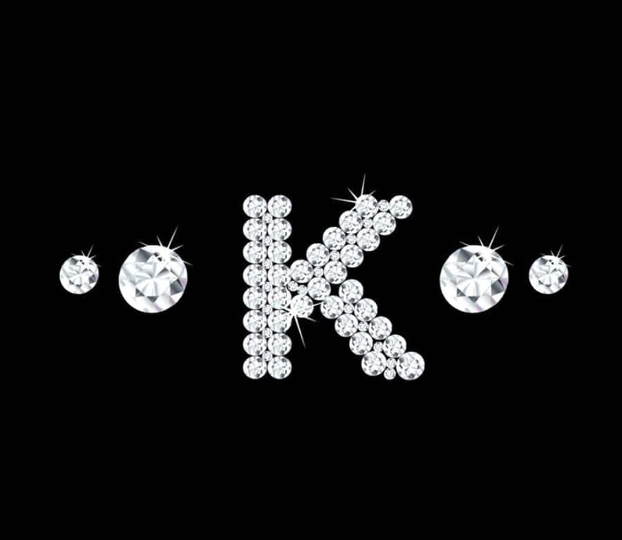 K 桌布 壁紙 — 由閃爍鑽石組成的字母K，背景為黑色，散落著寶石。