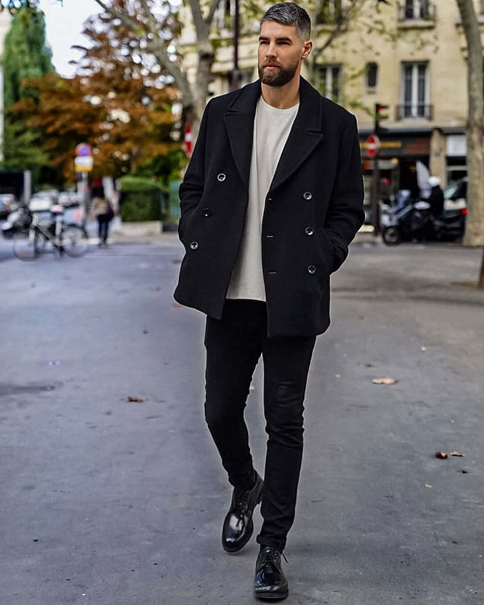 穿黑色大衣和靴子的男人在城市人行道上行走
