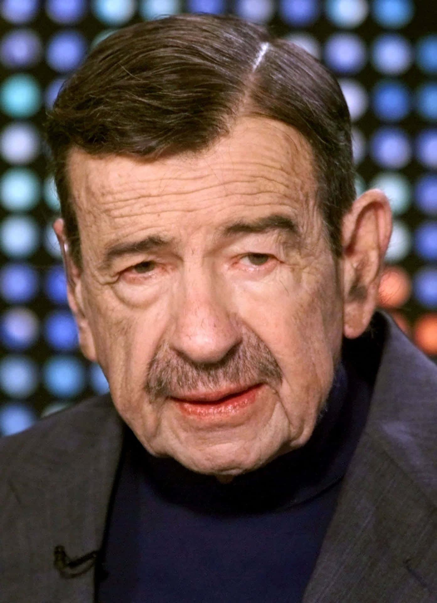 Walter Matthau 桌布 壁紙 — 男士鬍鬚特寫肖像，穿著深色高領毛衣和西裝，背景是模糊的彩色圓點。