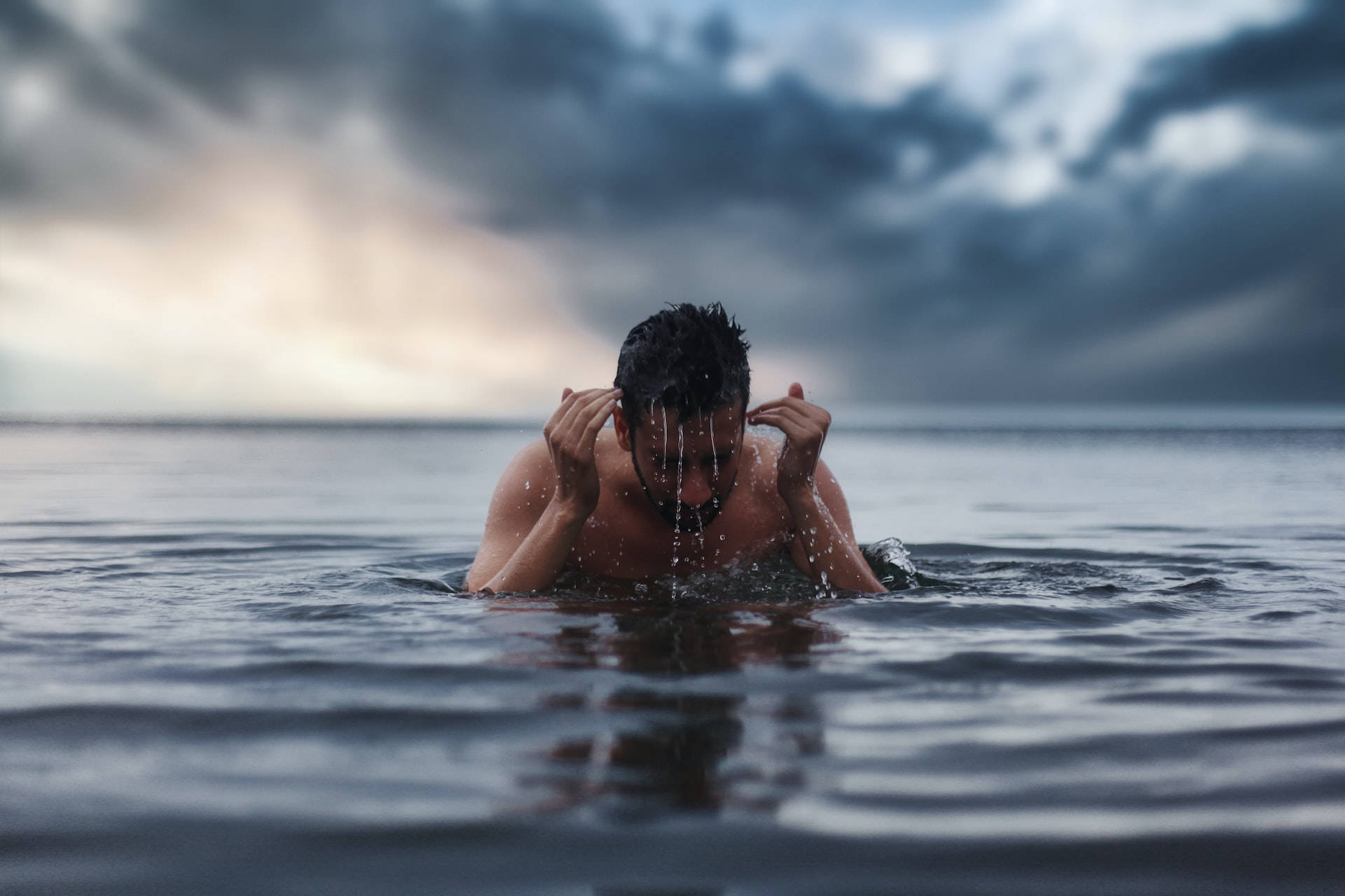 男子在暴風雨天空下在洶湧的海中游泳
