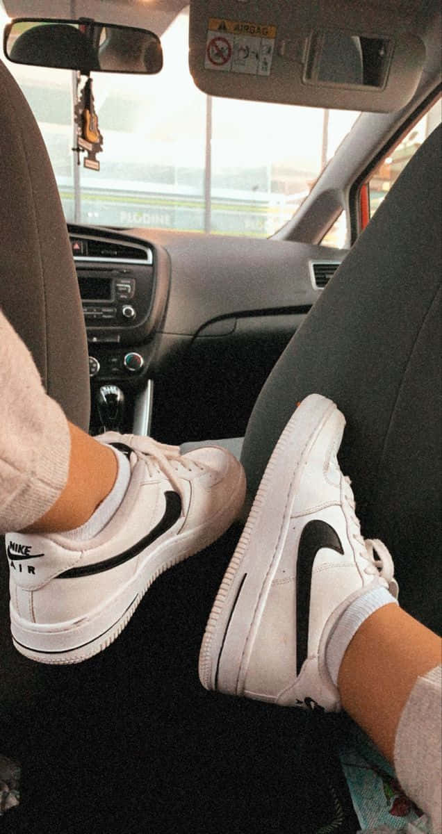穿著白色Nike運動鞋的雙腳放在汽車座椅上。