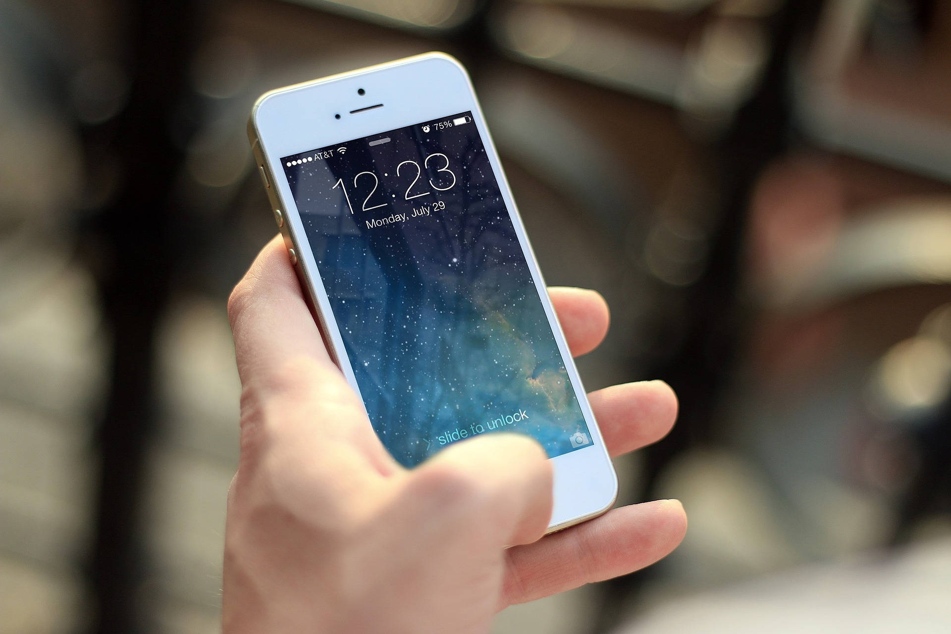 手拿著白色iPhone，帶有星空壁紙和解鎖提示。