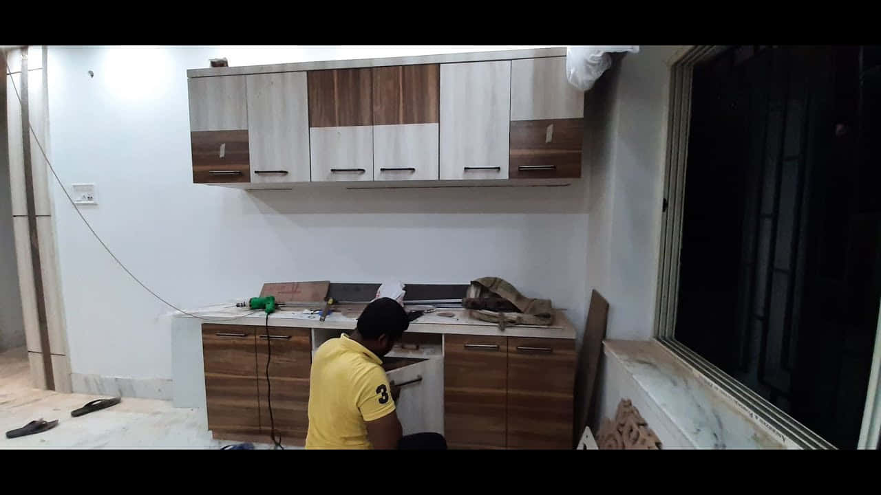 男子在夜間黑暗的房間裡安裝木製廚房櫥櫃。
