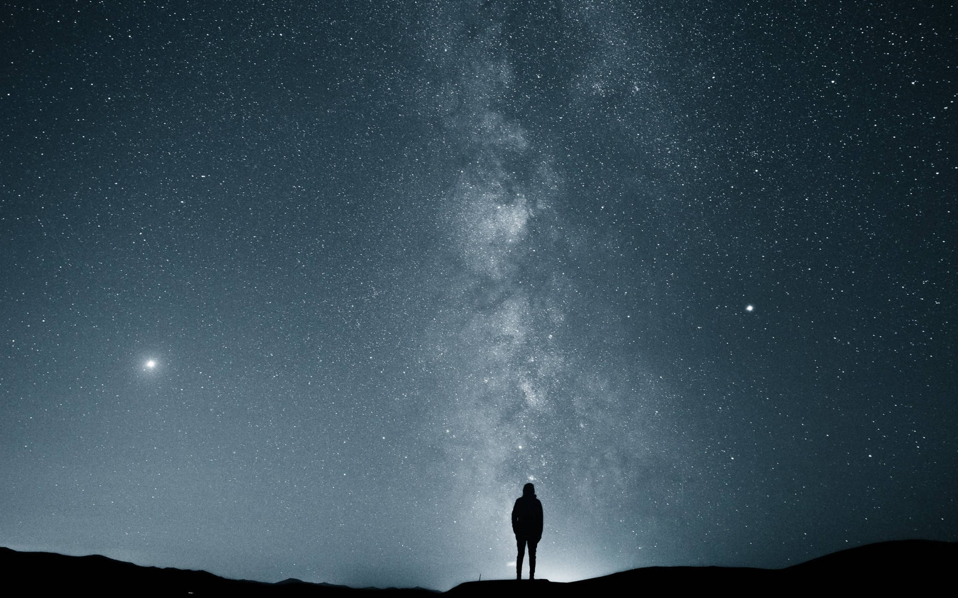 男子獨自仰望星空 壁紙 — 一個孤獨的身影站在山頂上，仰望佈滿銀河的壯麗星空。