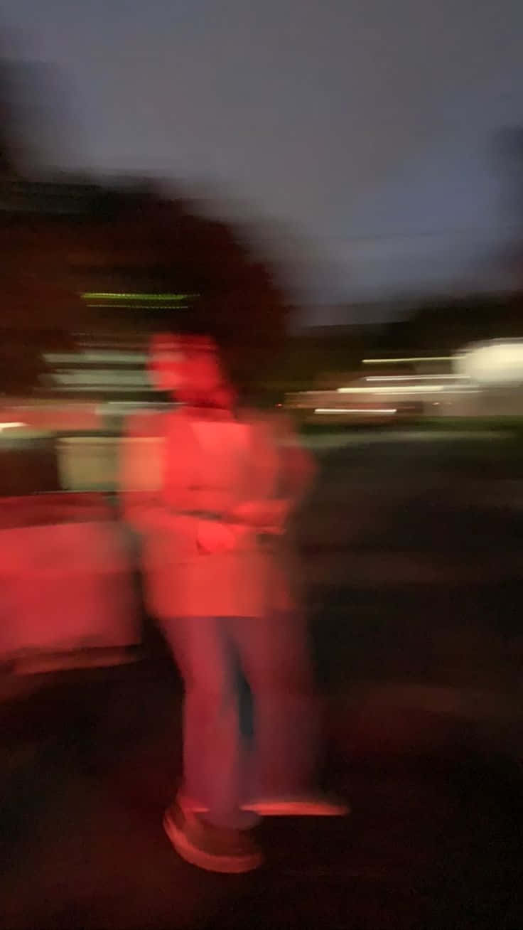 模糊的人站在紅色照明的城市夜景中，帶有條紋光線。