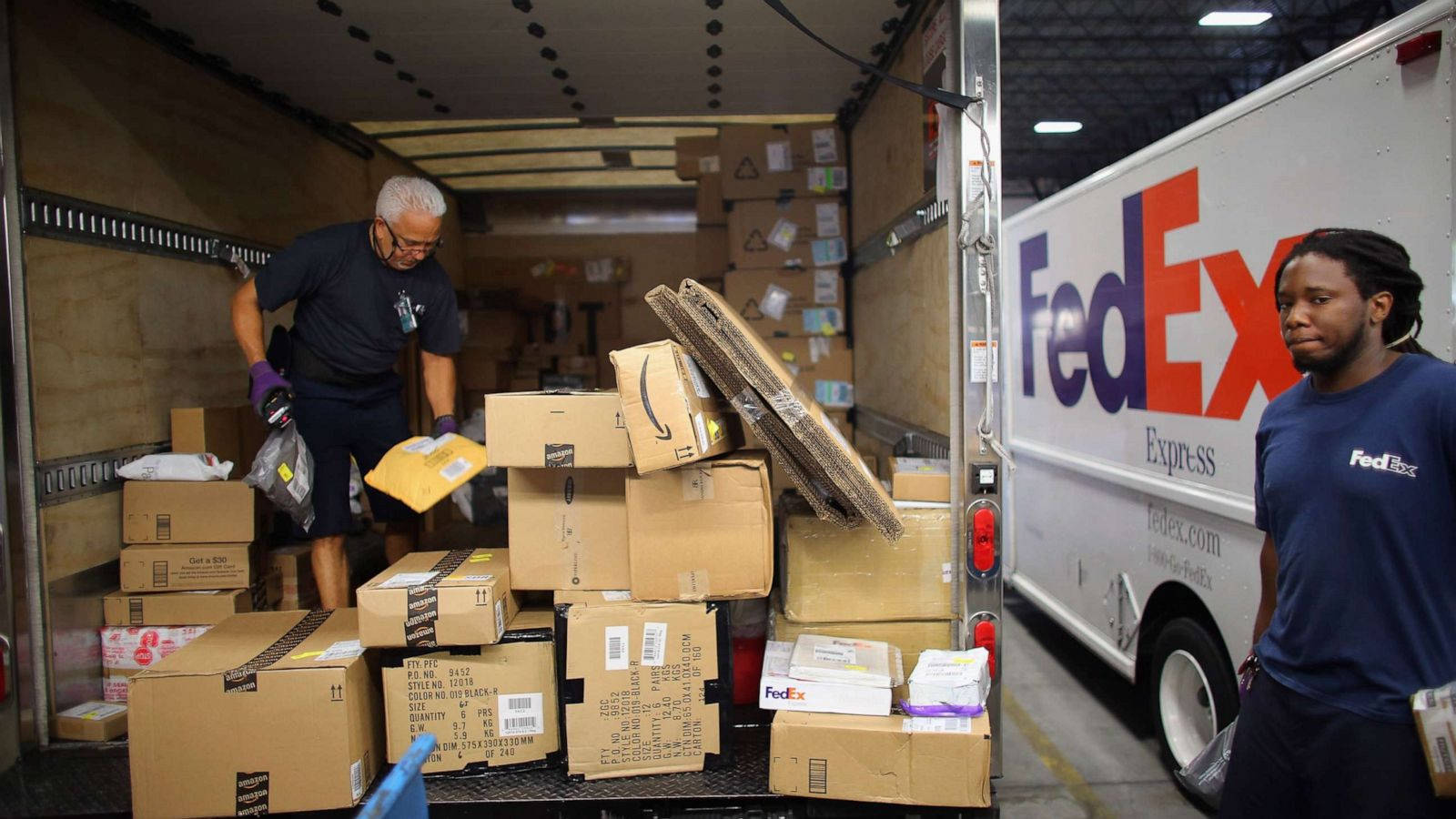 FedEx員工在倉庫內將包裹裝載到送貨車上。