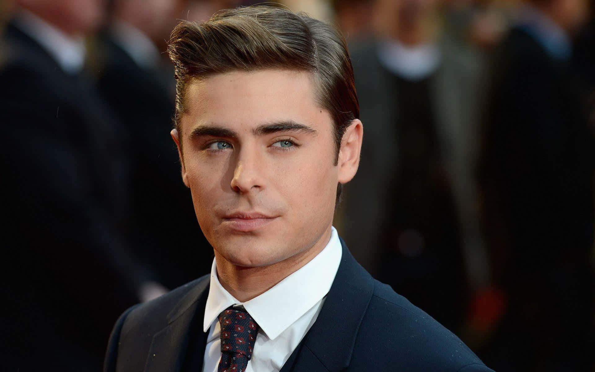Zac Efron 在正式活動中穿著深色西裝和圖案領帶。