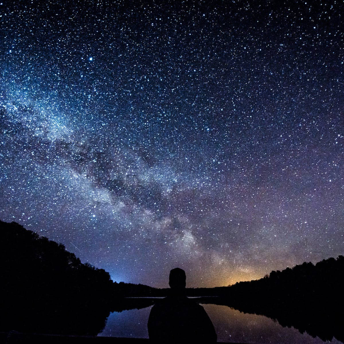 男子與繁星夜空通用手機背景 壁紙 — 一個孤獨的身影凝視著銀河系，在平靜的湖面倒映的星空下拱起。