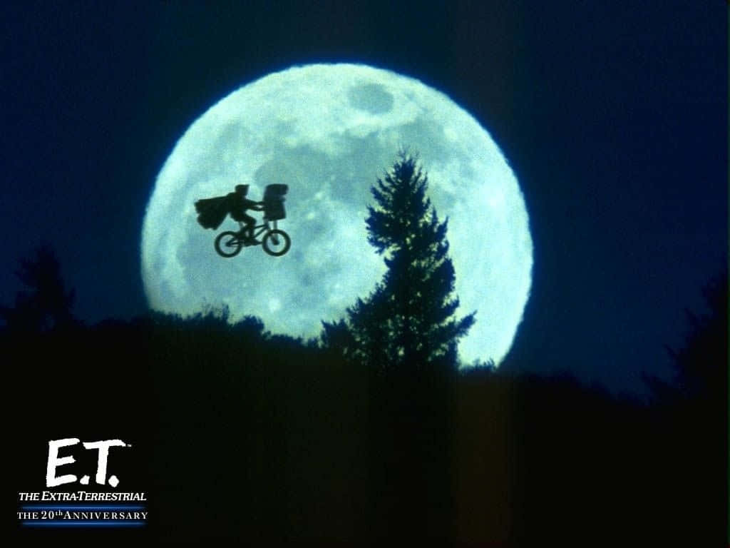 小孩和外星人騎單車飛向巨大月亮，越過夜晚的森林。