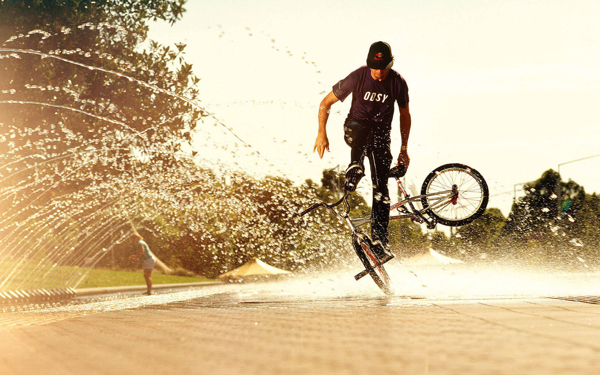 BMX車手在日落時分的公園噴泉上表演特技。