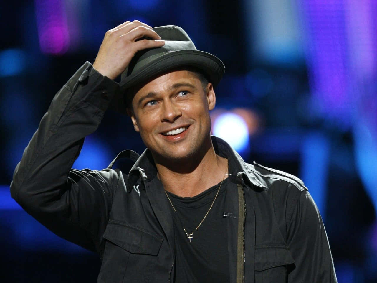 Brad Pitt 桌布 壁紙 — 畢彼特在充滿活力的藍色燈光舞台上溫暖微笑，同時傾斜他的軟呢帽。