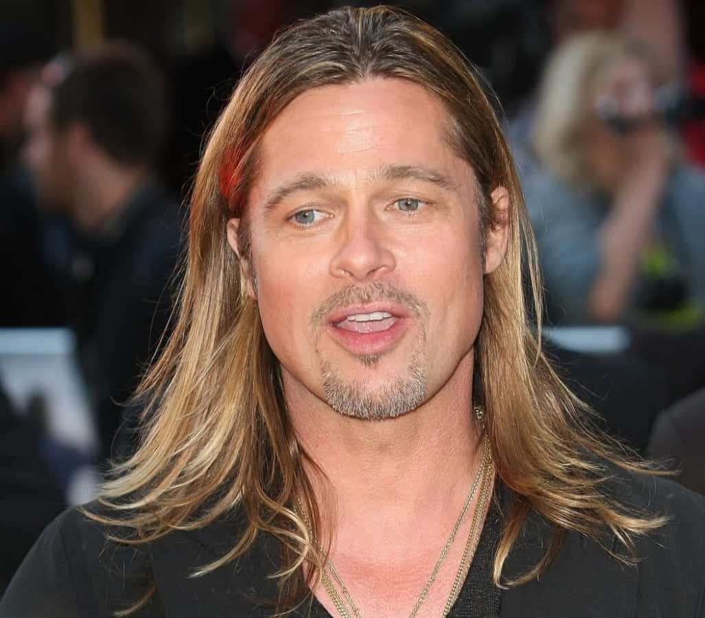 Brad Pitt 桌布 壁紙 — 畢彼特留著金色長髮和山羊鬍，身穿黑色外套，對著鏡頭微微一笑。