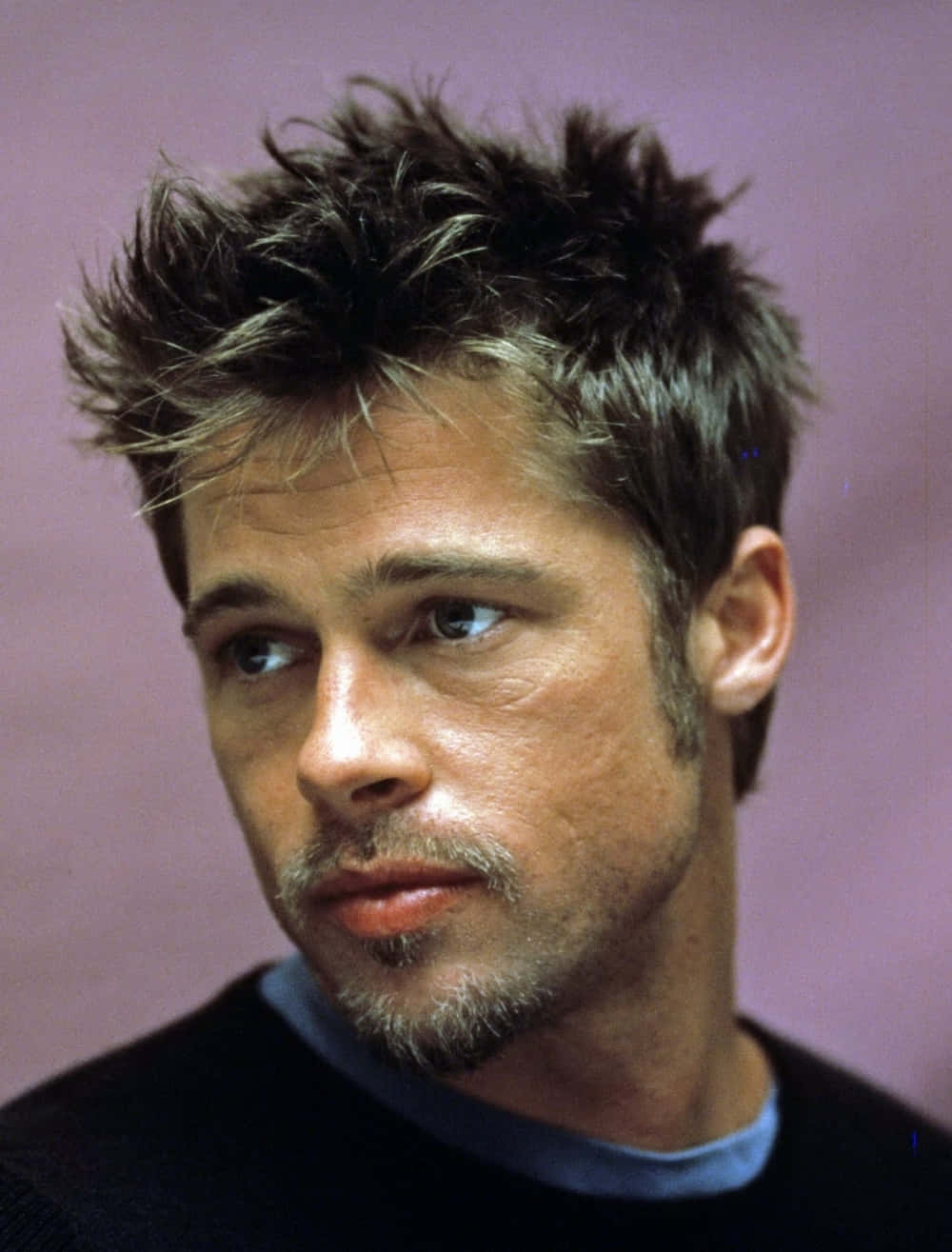 Brad Pitt 桌布 壁紙 — 畢彼特的近距離肖像照，一頭凌亂的深色頭髮和鬍渣，背景是柔和的紫色。