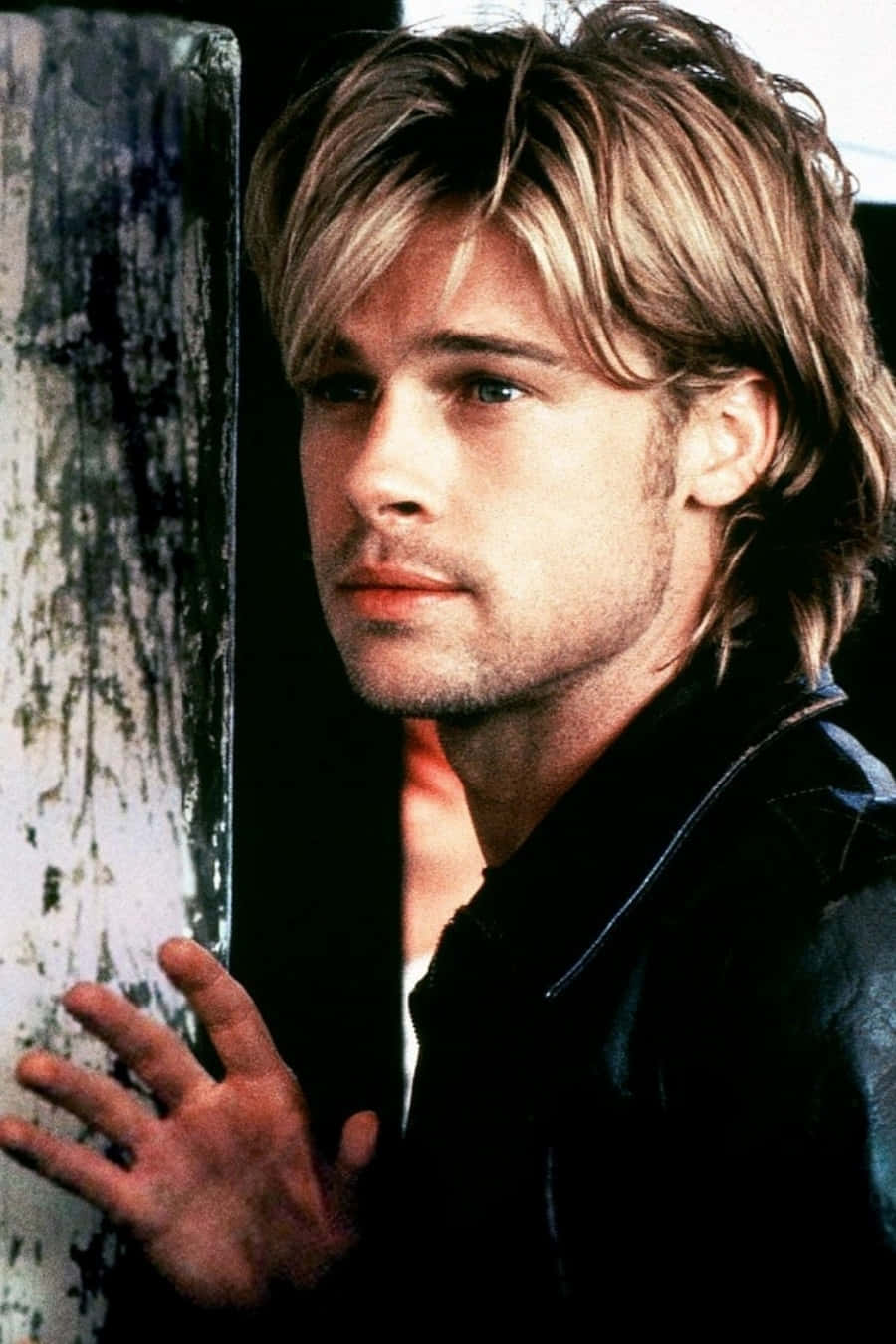 Brad Pitt 桌布 壁紙 — 畢彼特靠喺一幅風化嘅牆上，帶住沉思嘅目光，營造出憂鬱嘅電影感肖像。