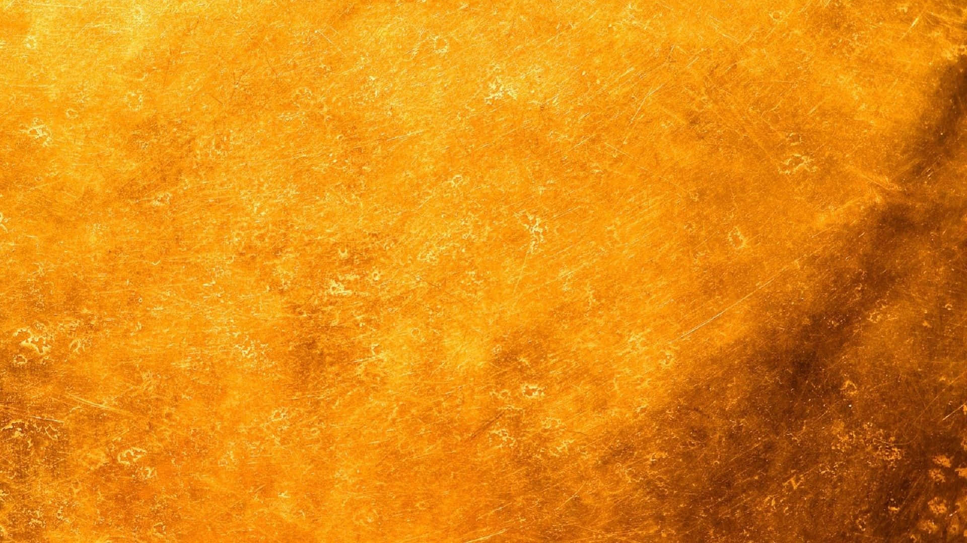 帶有刮痕和溫暖漸變色的金色紋理表面。