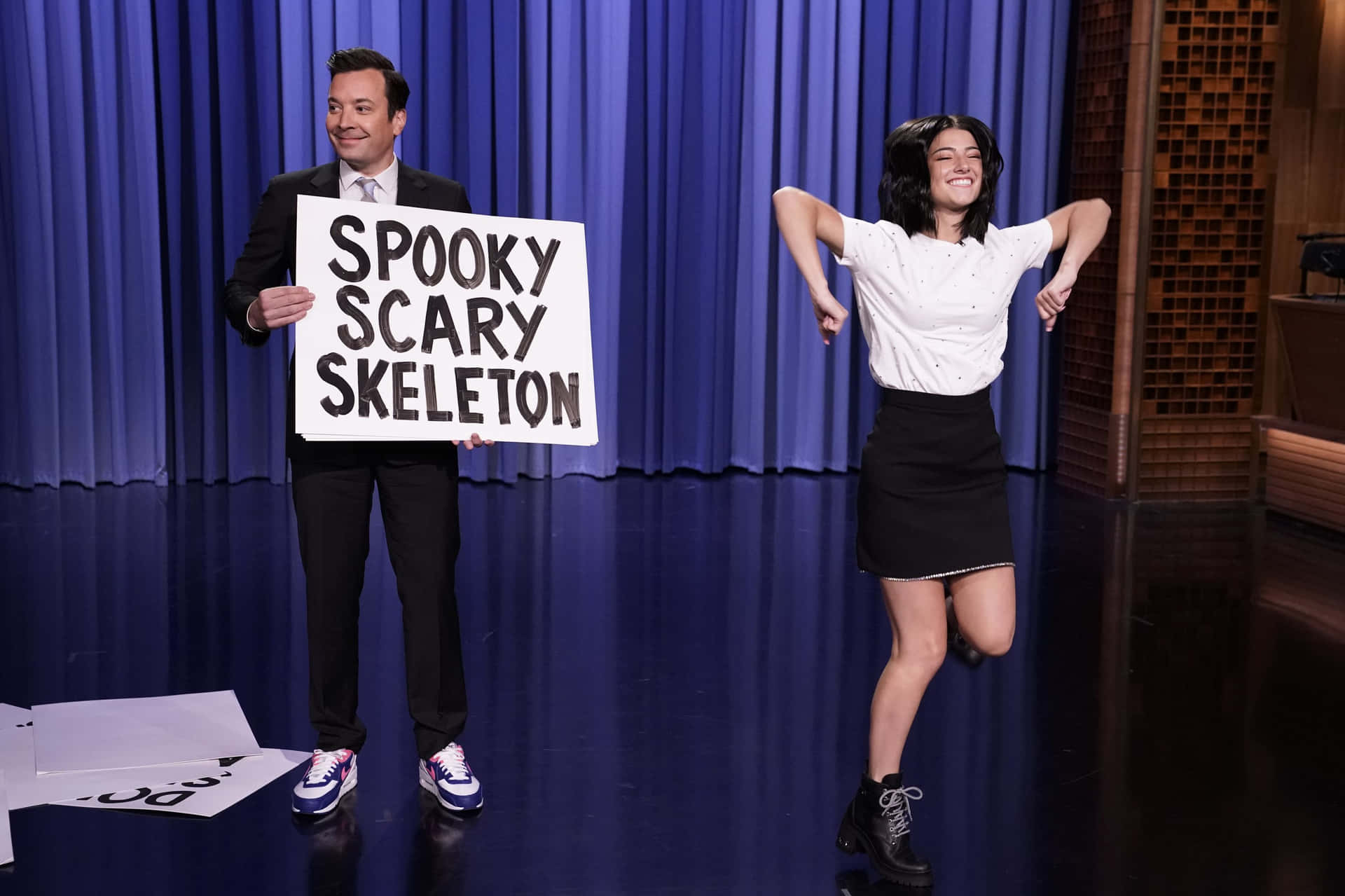 男子舉著spooky scary skeleton牌子，女子在舞台上跳舞。