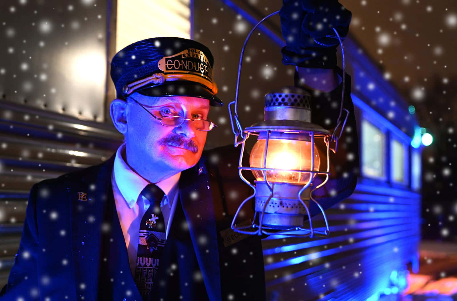 登上極地特快車 壁紙 — 一位身穿復古制服的列車長在雪夜背景下，身後有一列火車，手持發光燈籠。