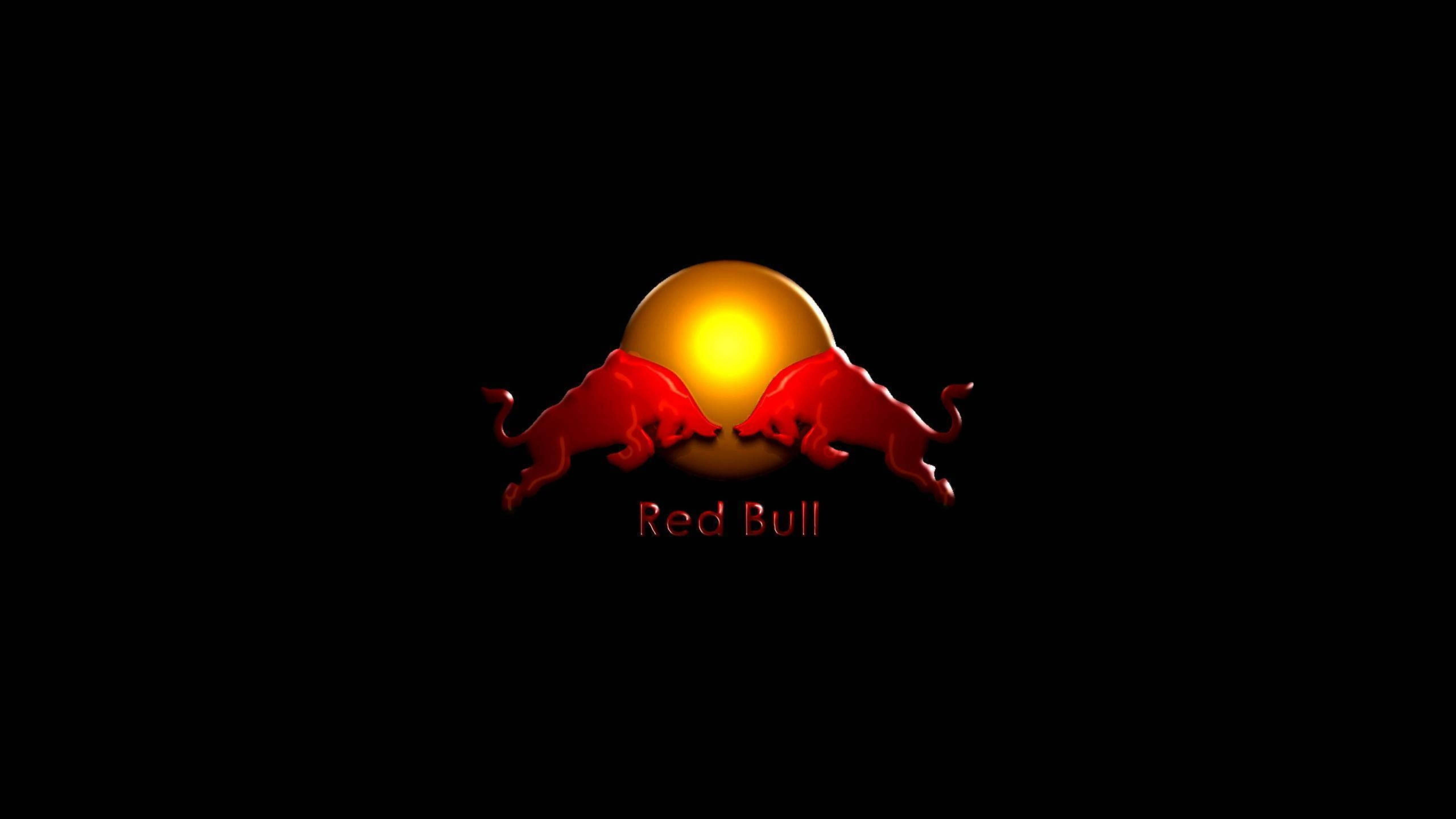 發光 3D 紅牛 壁紙 — 兩隻紅色衝鋒的公牛在發光的金色太陽周圍面對面，黑色背景，下方有「Red Bull」文字。
